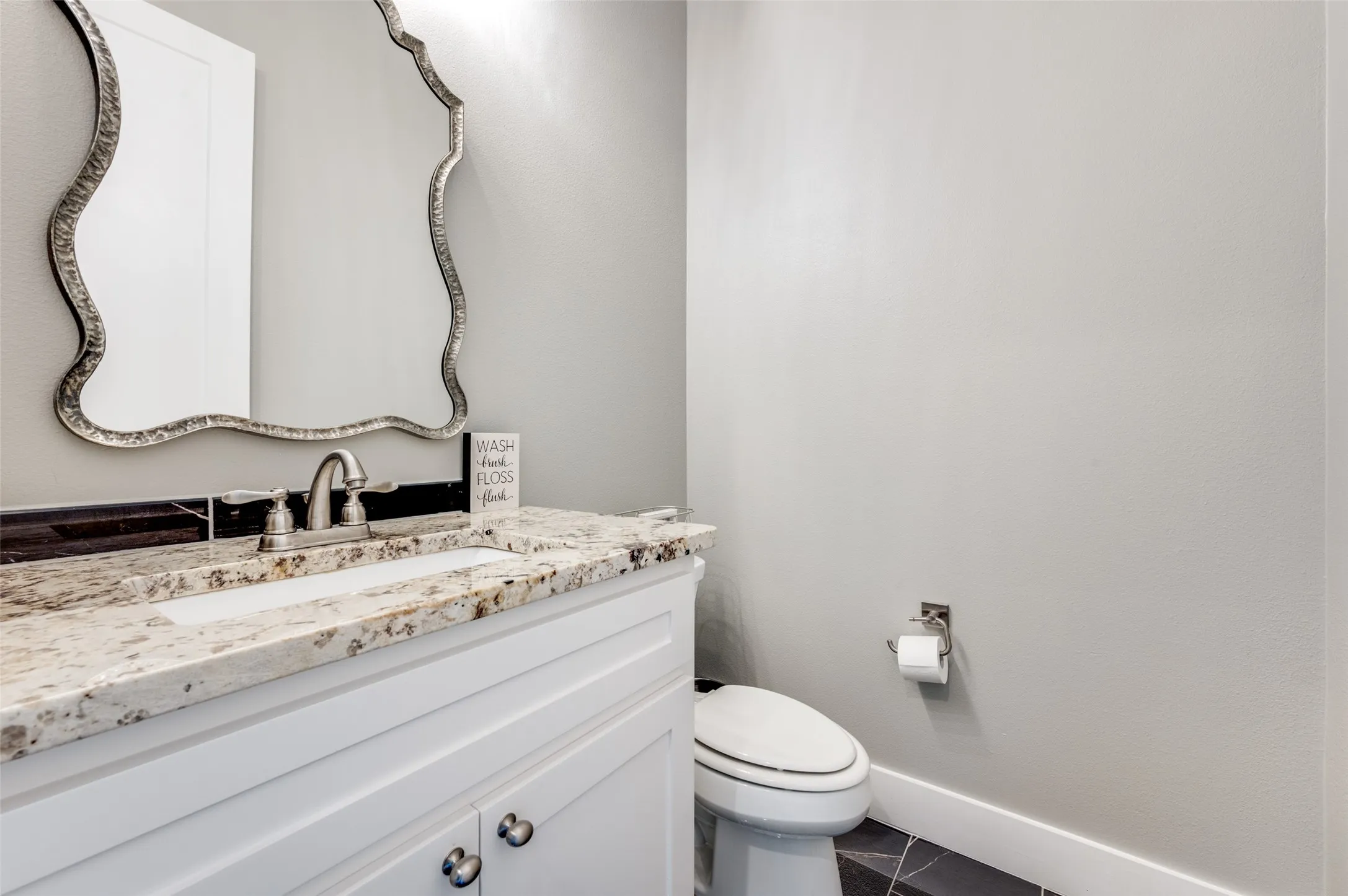 White vanity with decorative pulls, granite countertop, undermount sink, and brushed nickel faucet