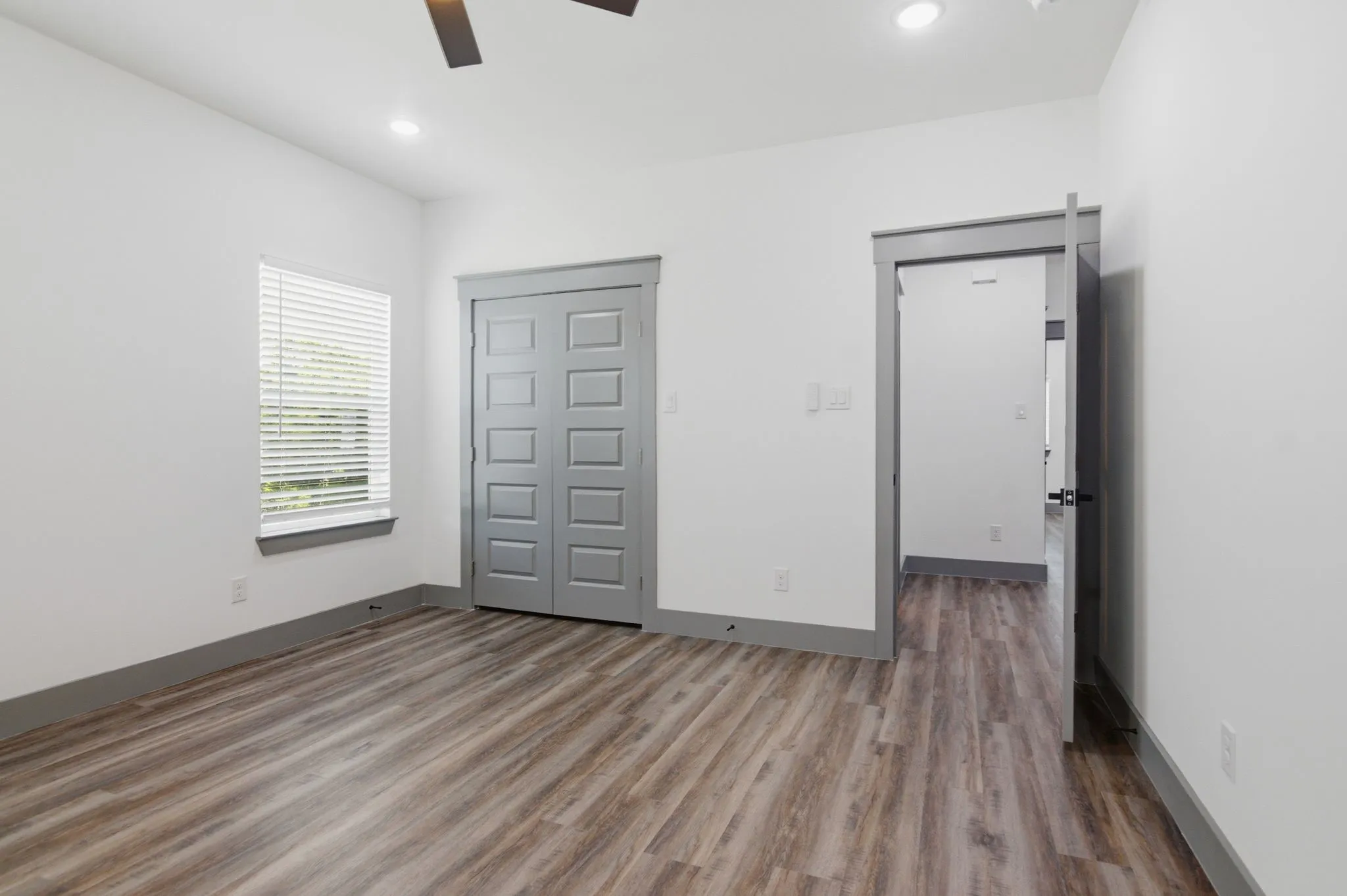 Wood-finish flooring, recessed lighting, ceiling fan, window with blinds, and solid panel closet doors
