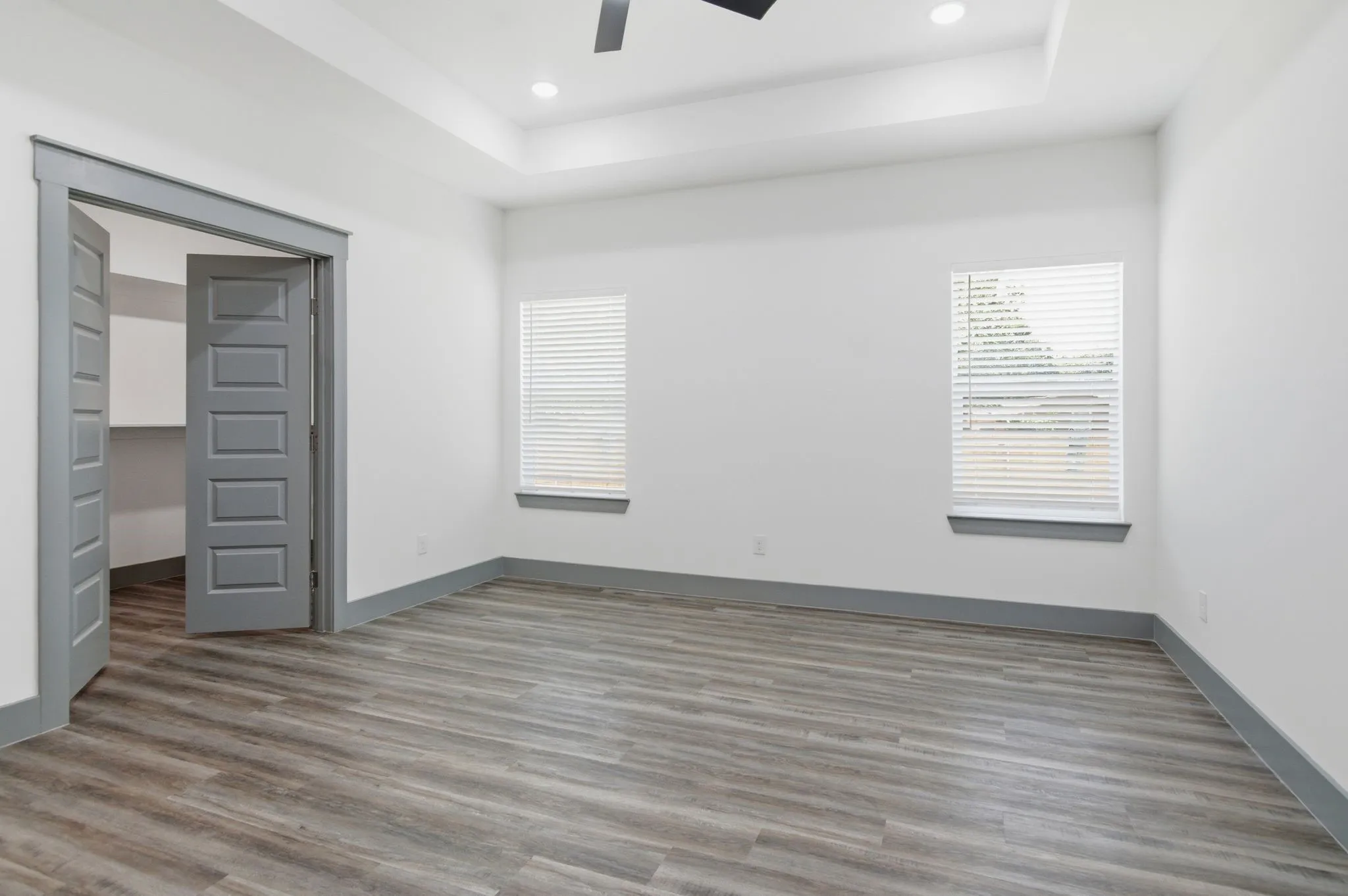 Wood-finish flooring, recessed lighting, tray ceiling, and a five-panel interior door