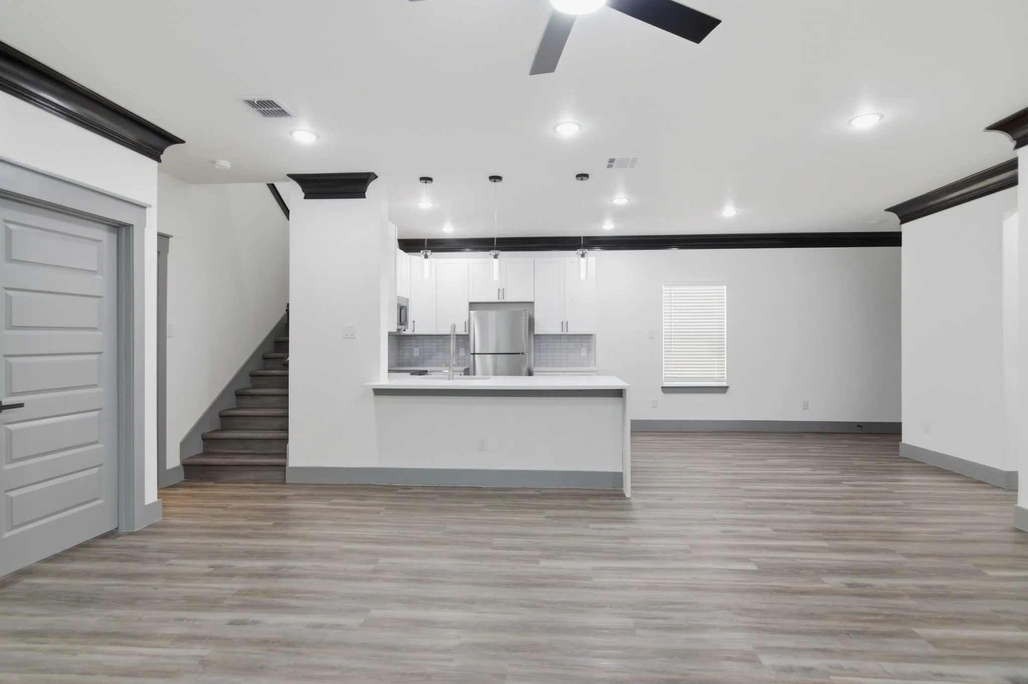Open-concept living area with wood-finish flooring, recessed lighting, and a ceiling fan