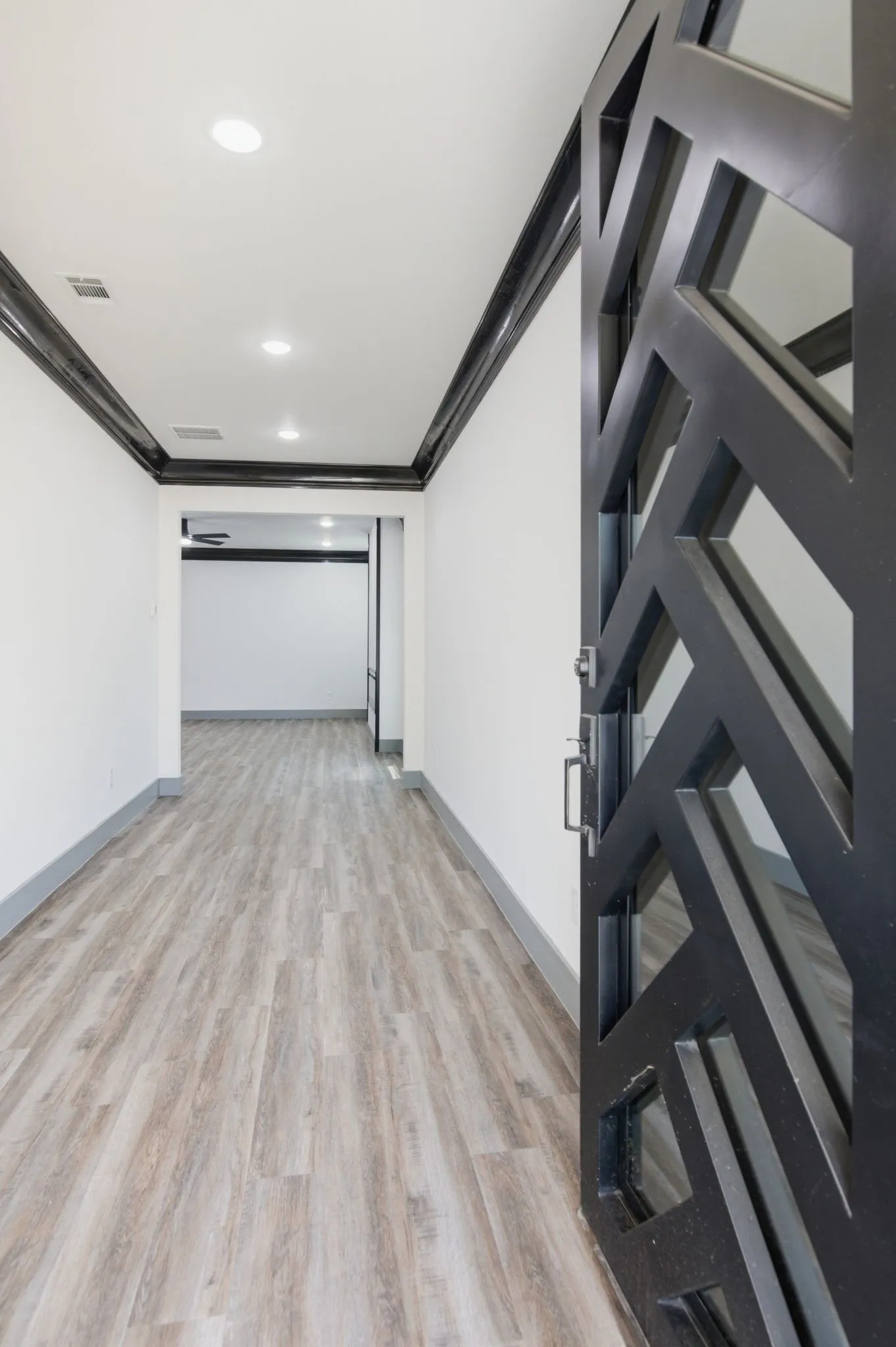 Modern decorative security door, recessed ceiling lighting, light wood-finish flooring, and crown molding