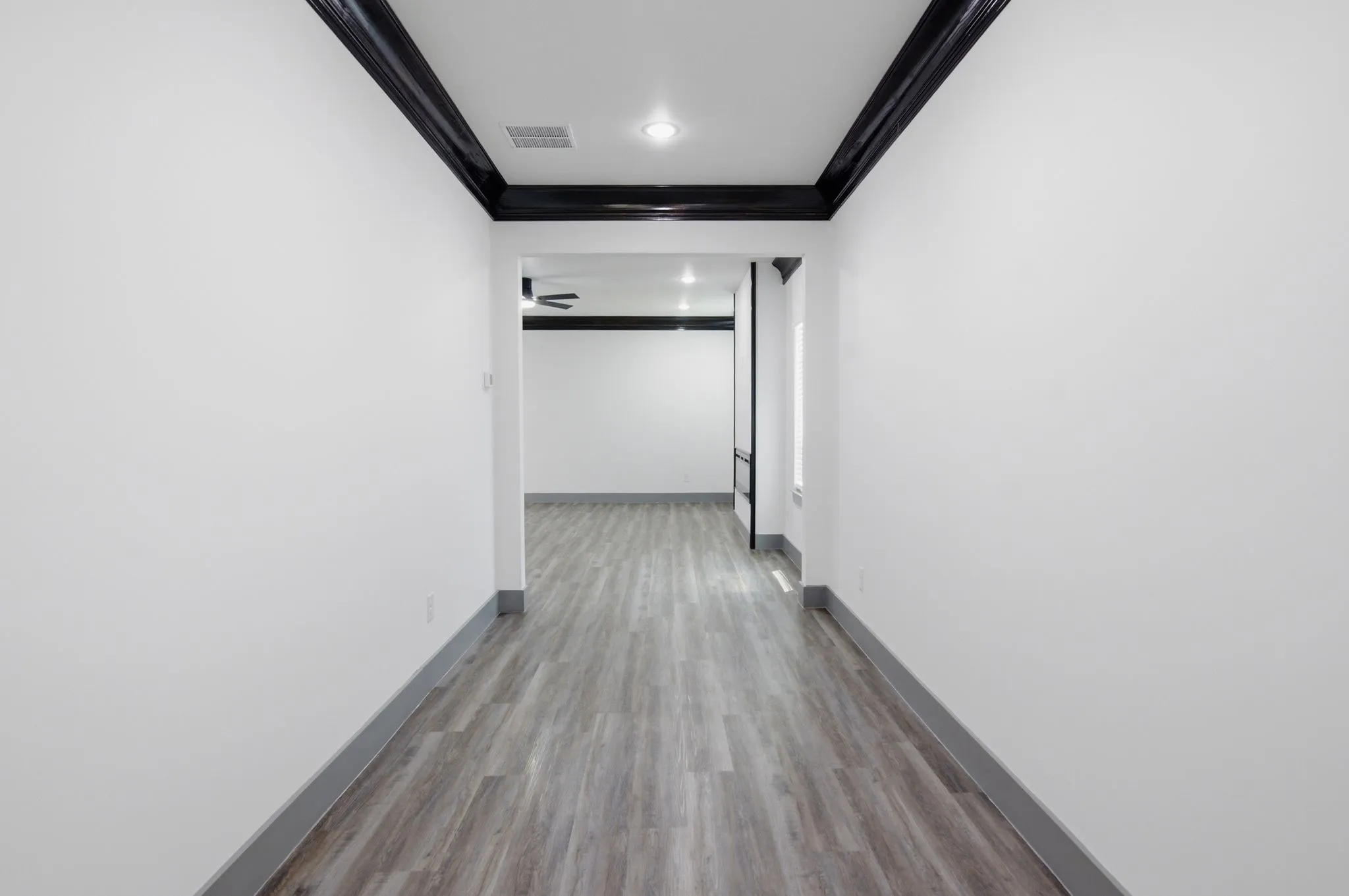 Wood-finish flooring with dark baseboards, recessed lighting, and crown molding