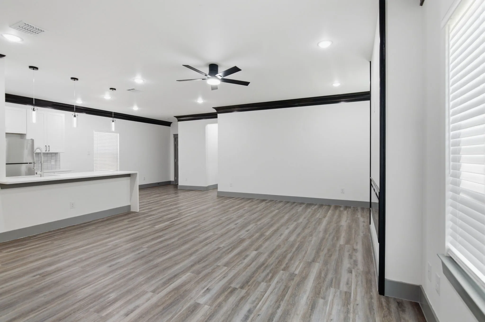 Open-concept living area featuring wood-finish flooring, recessed lighting, and a ceiling fan