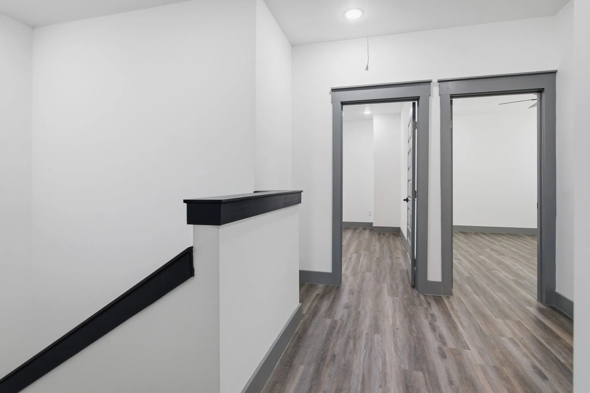Wood-finish flooring throughout, solid core doors with panel detailing, recessed ceiling lighting, and contrasting dark trim