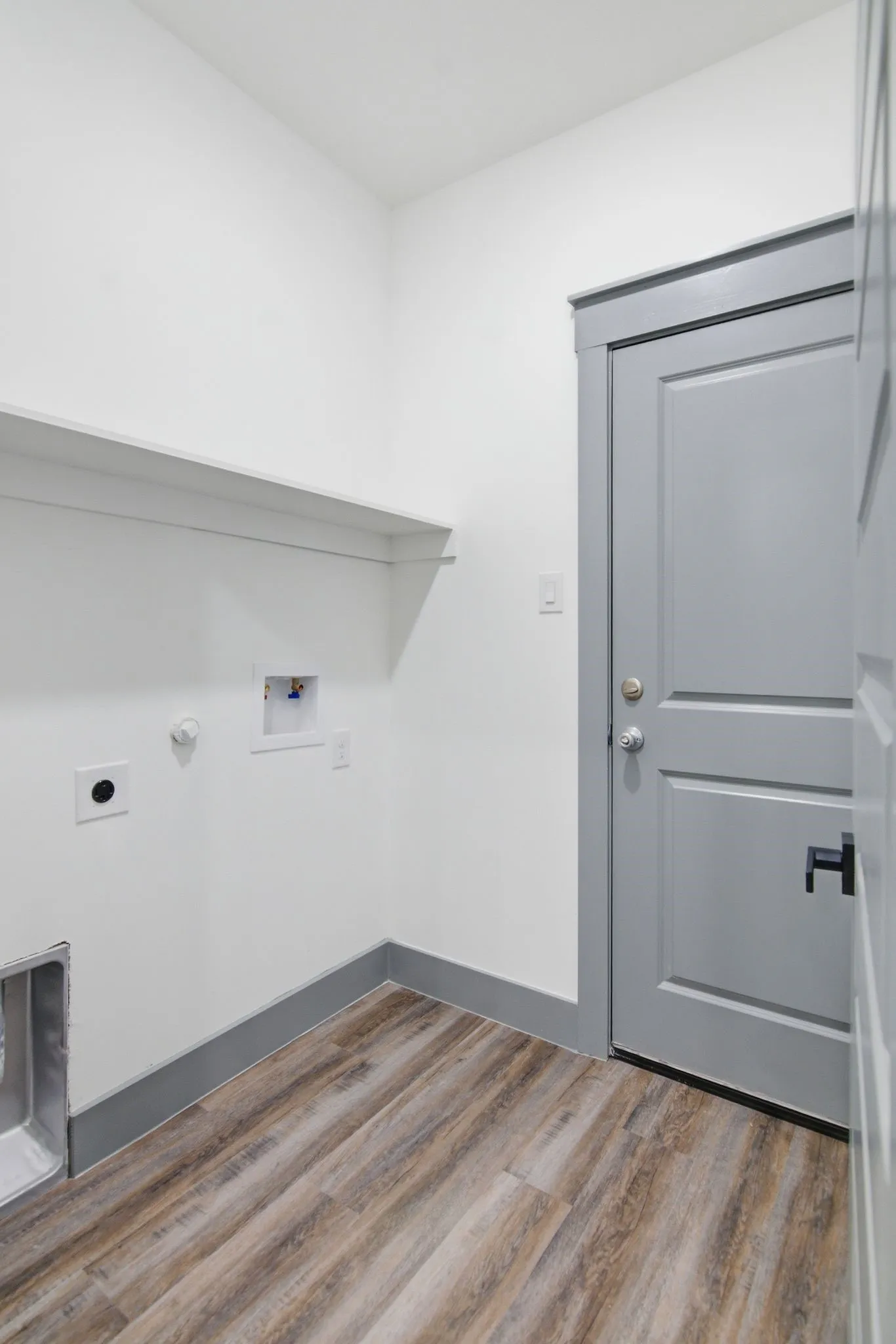 Wood-finish flooring, built-in shelving, and a paneled door with contemporary hardware
