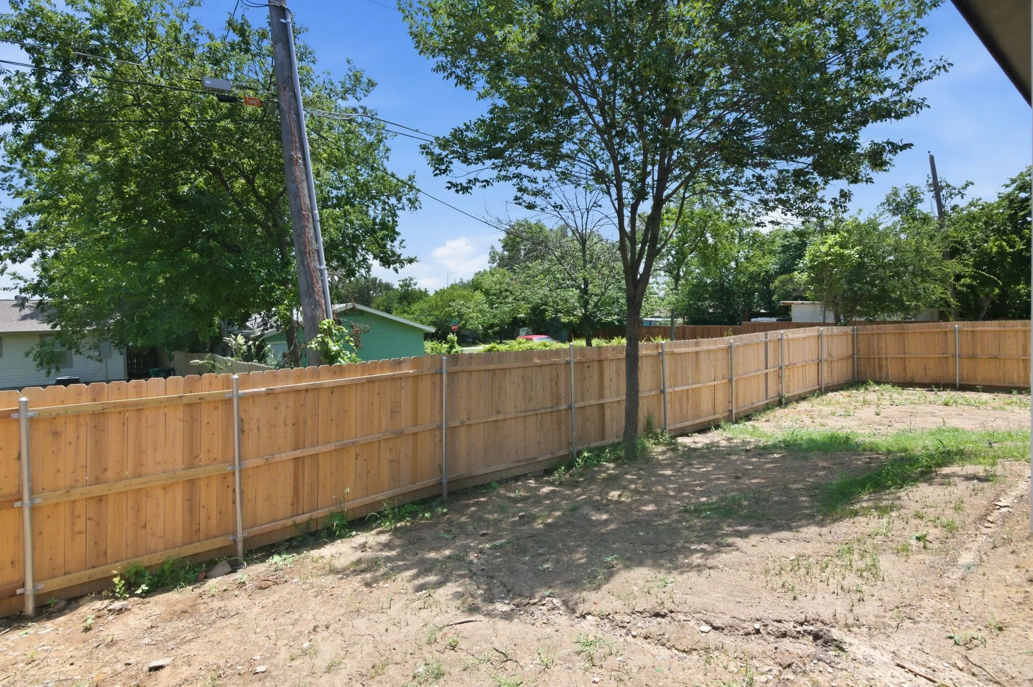 Expansive outdoor space featuring wood privacy fencing and mature trees
