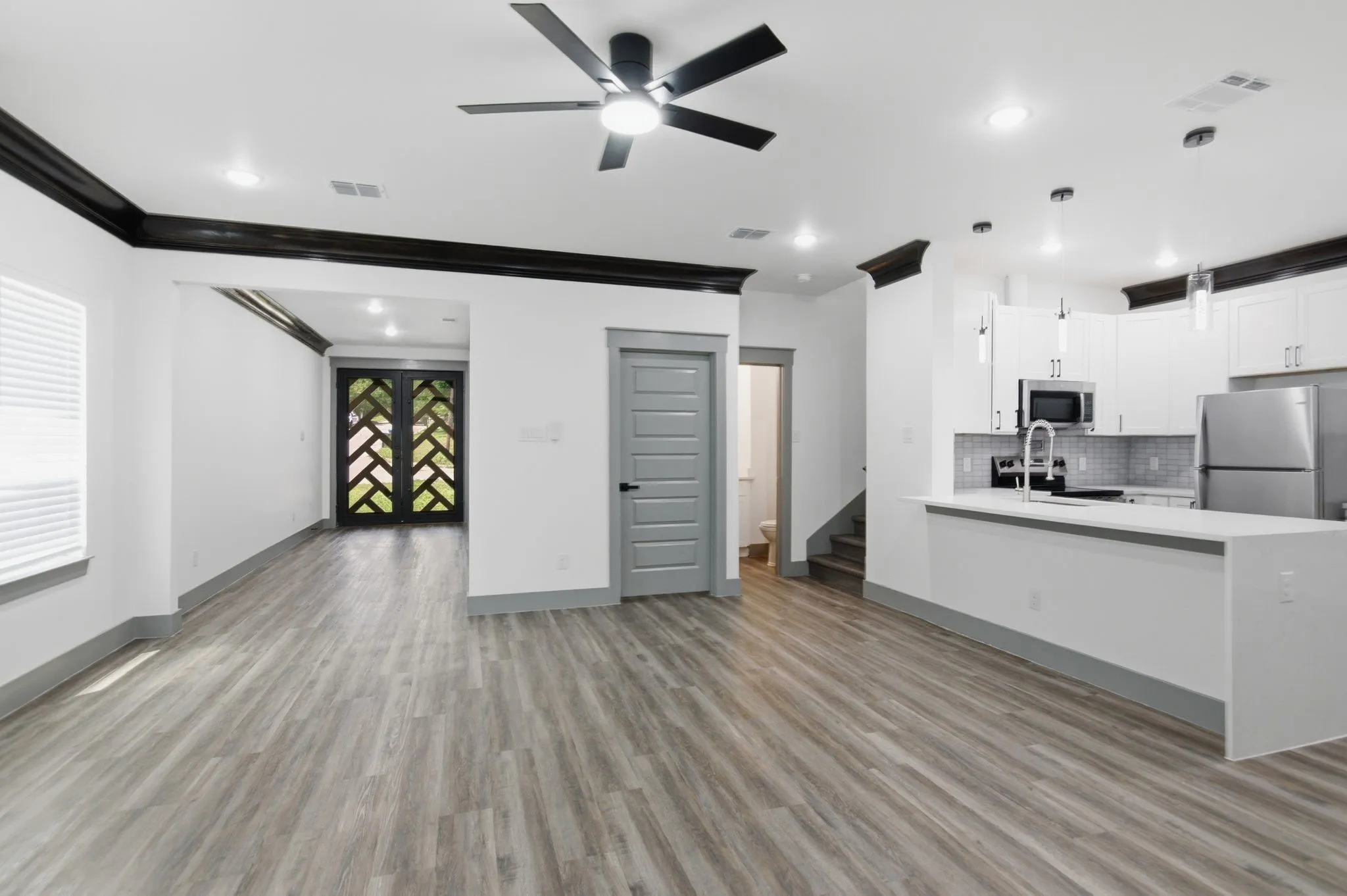 Open-concept living space with wood-finish flooring, recessed lighting, and a ceiling fan
