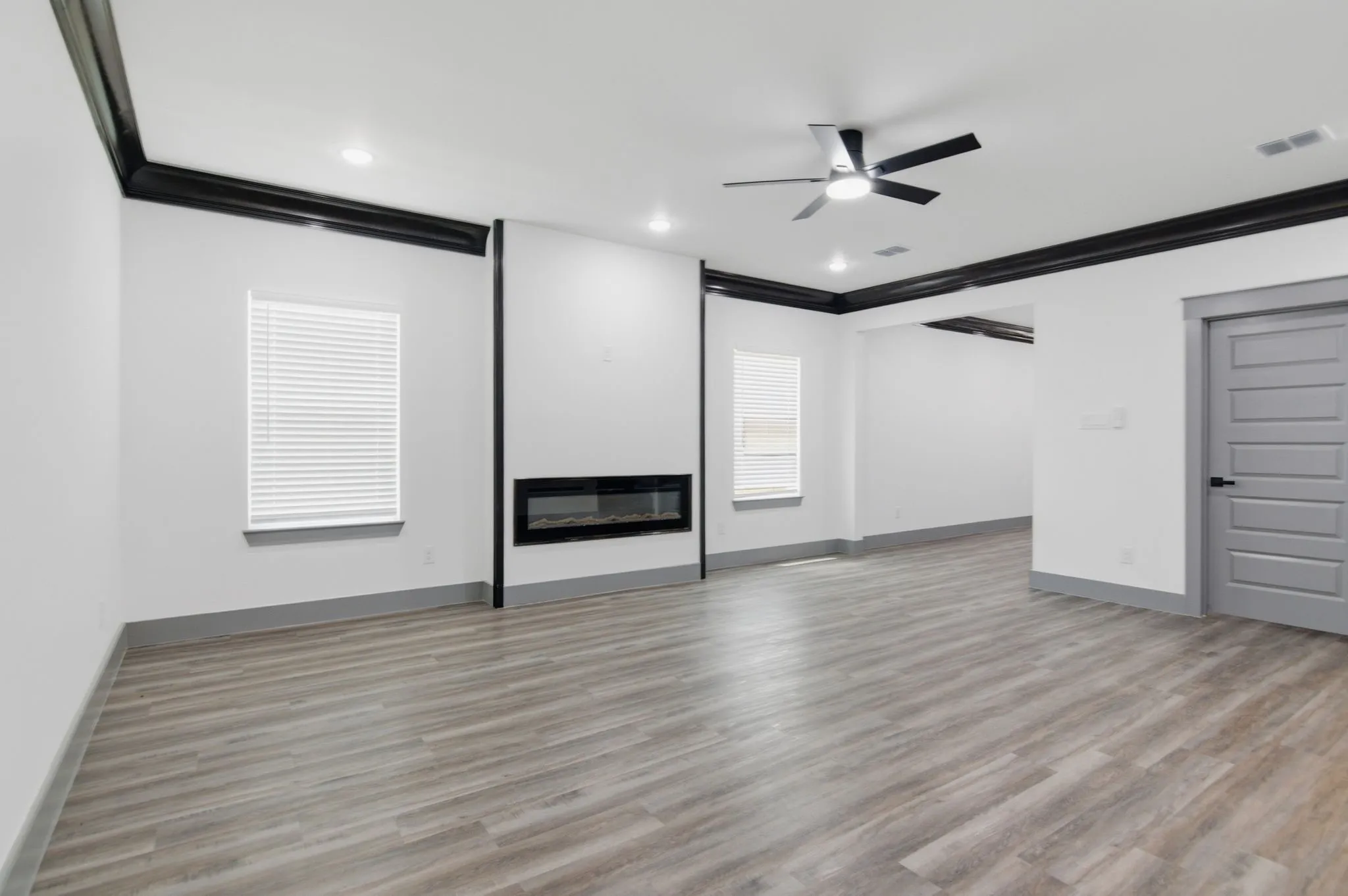 Spacious room featuring wood-finish flooring, a built-in linear fireplace, recessed lighting, and a ceiling fan