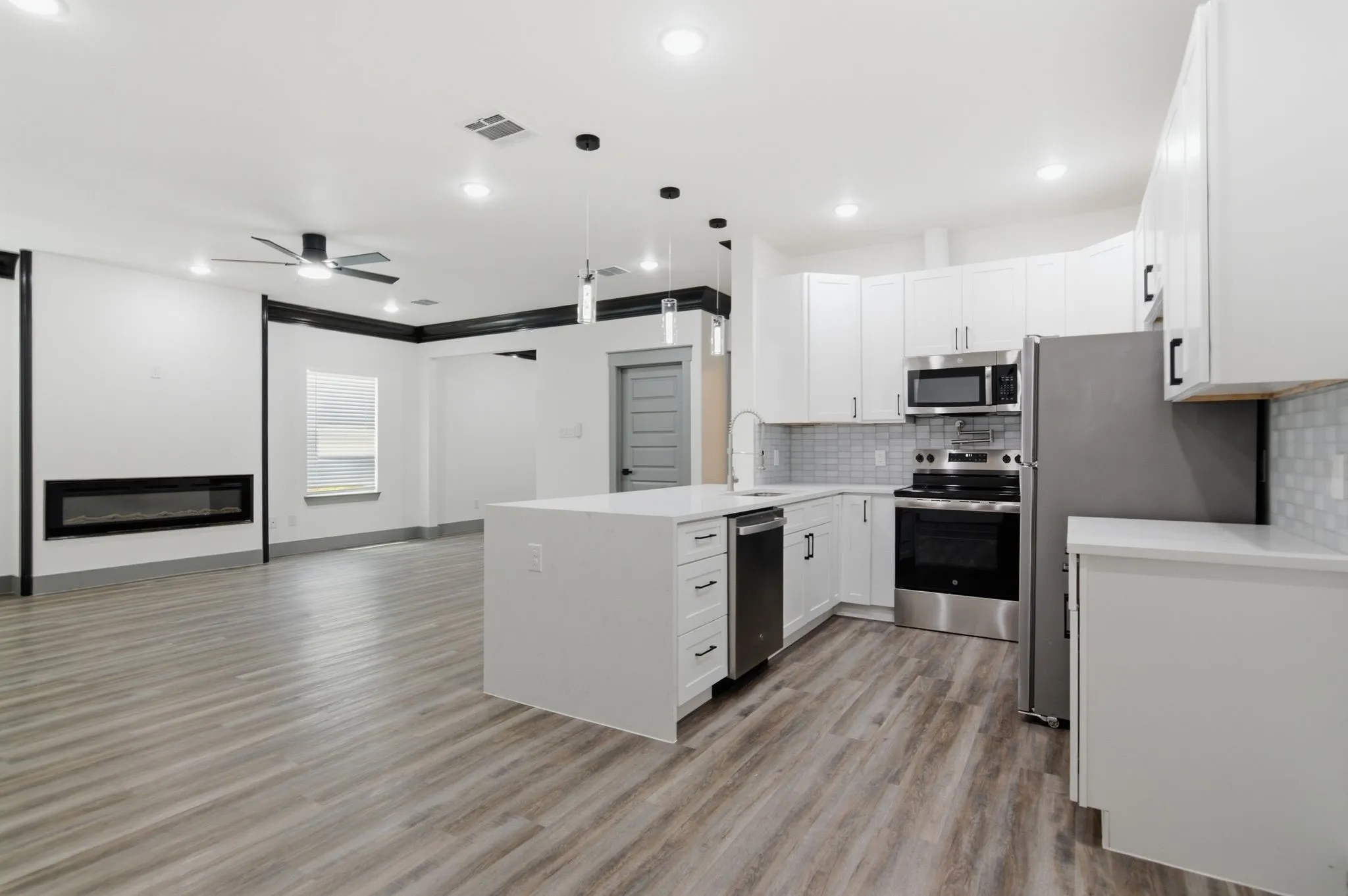 Open-concept living area with wood-finish flooring, a linear electric fireplace, and recessed lighting