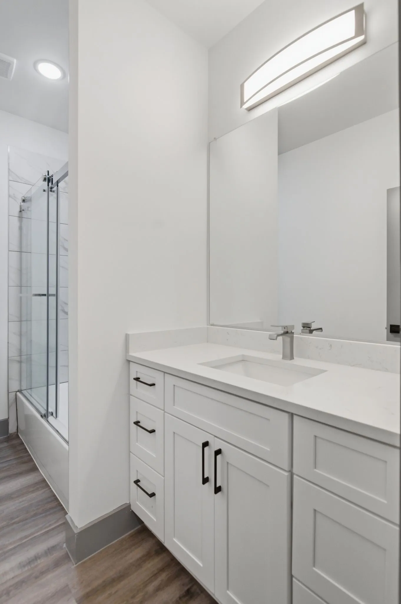 White vanity with integrated sink, chrome faucet, and black hardware