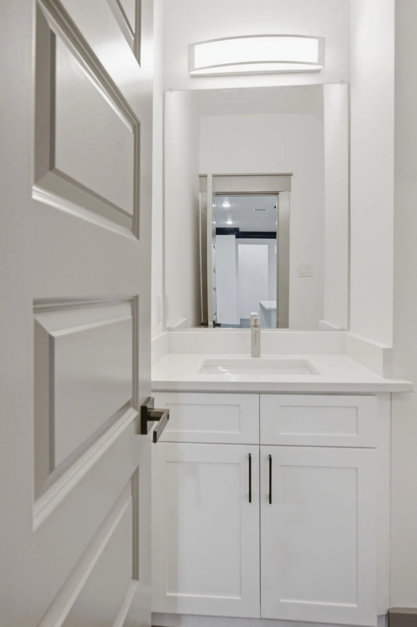 White vanity with a rectangular undermount sink, countertop, and a single-handle faucet