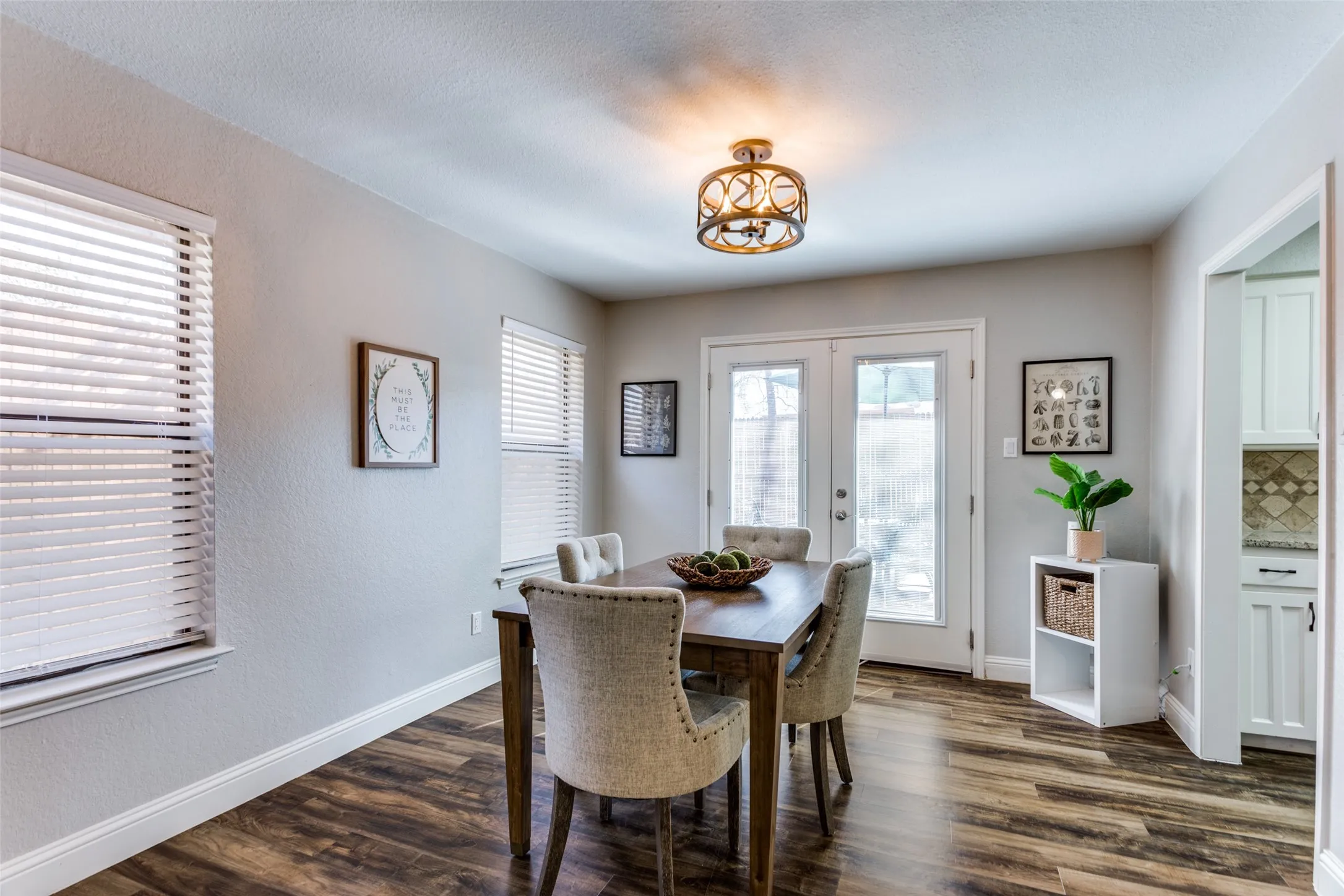 Wood-finish flooring, white double-pane French doors, and a decorative ceiling light fixture