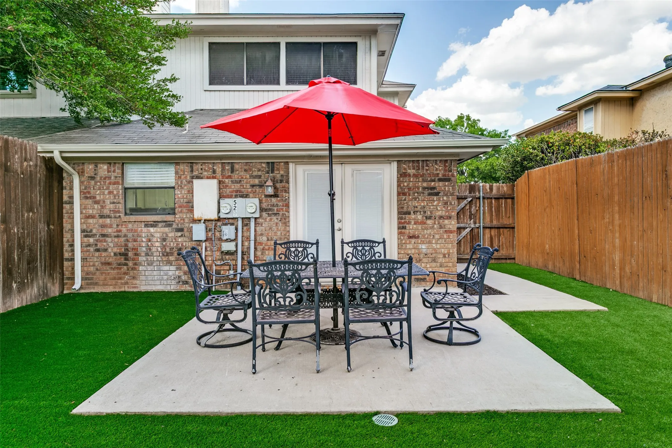 Expansive backyard featuring artificial turf, a concrete patio, and a privacy fence