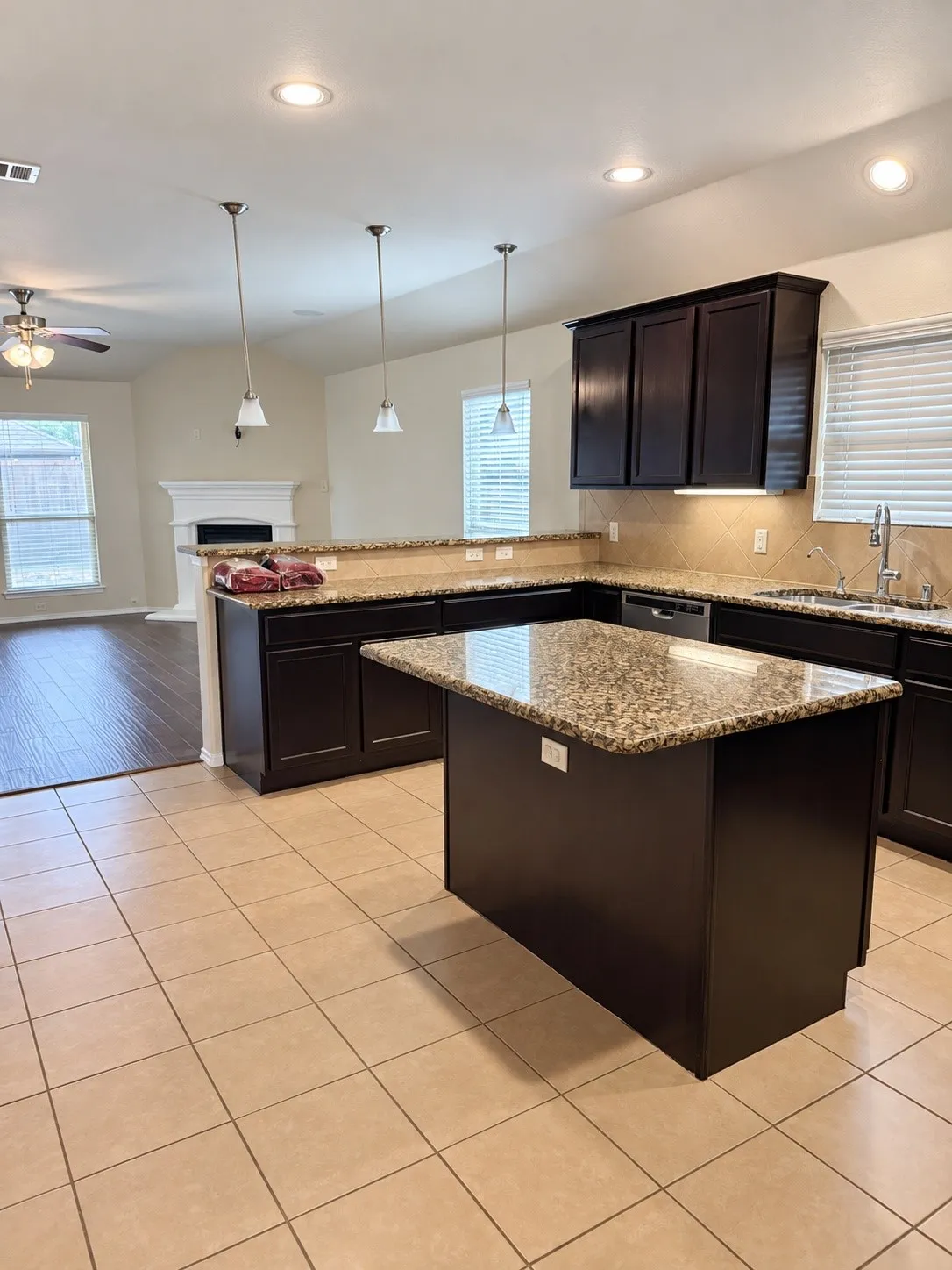 Kitchen featuring a central island, dark wood-finish cabinetry, granite countertops, and tile flooring