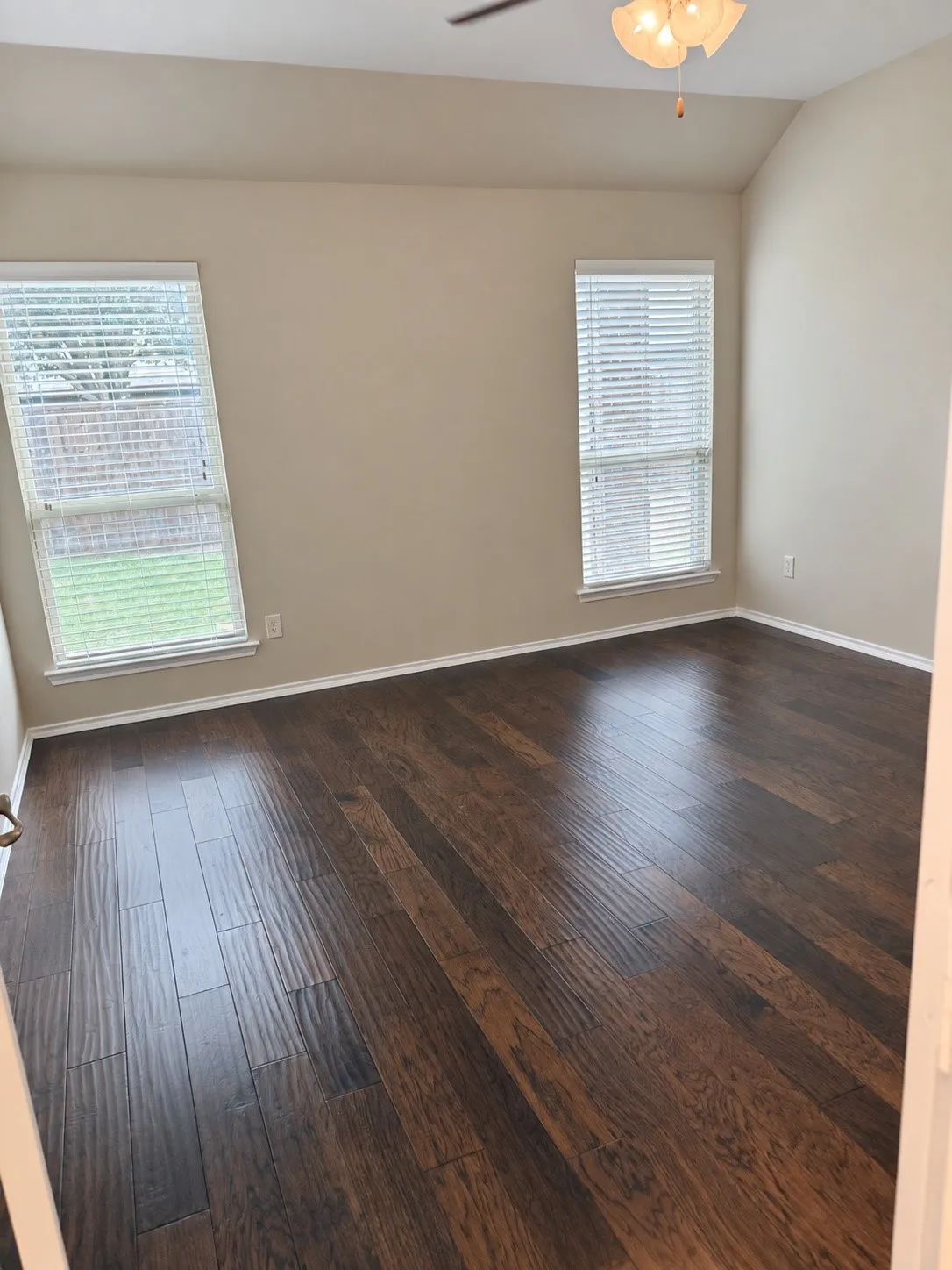 Wood-finish flooring, vaulted ceiling, and dual windows with blinds