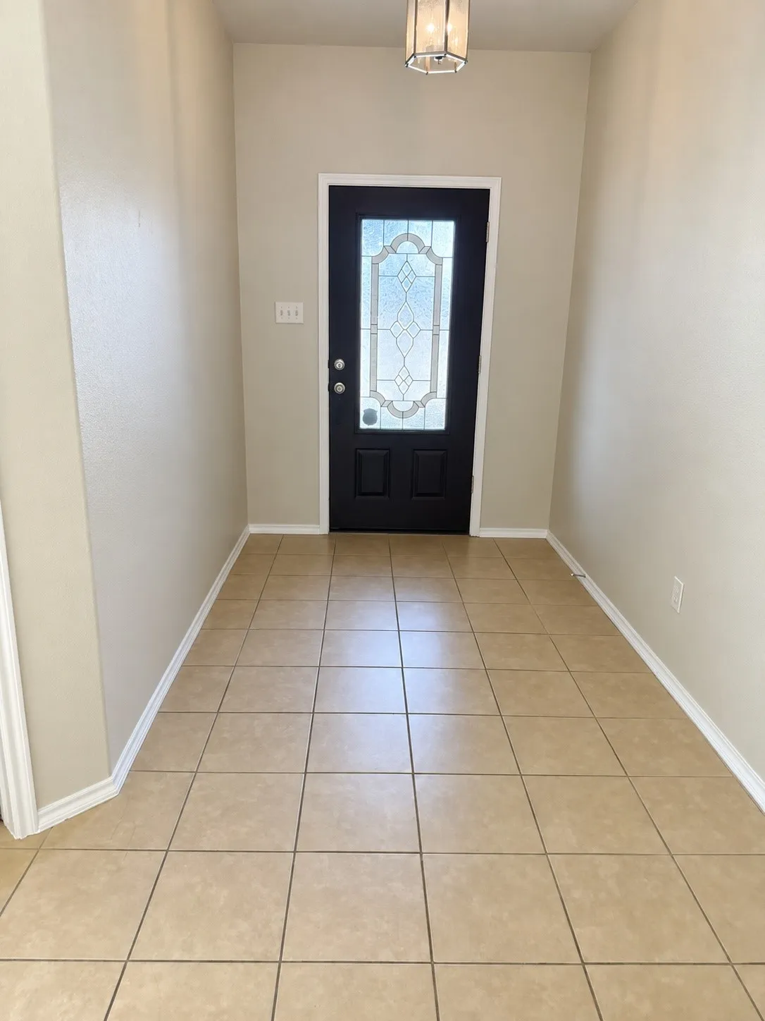 Entryway with ceramic tile flooring, a black paneled door featuring decorative glass, and a flush mount ceiling light