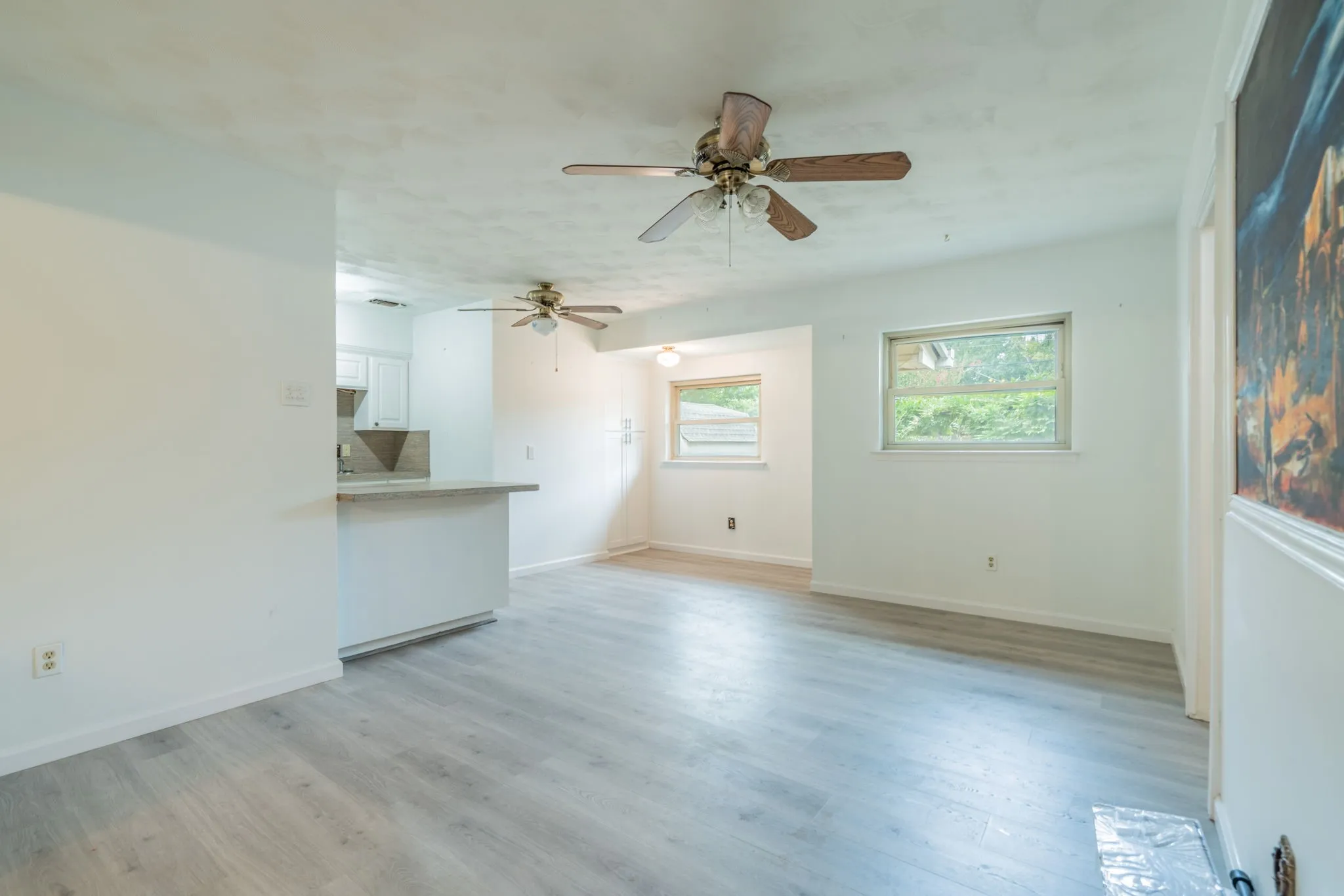 Light wood-finish flooring with white walls and dual ceiling fans