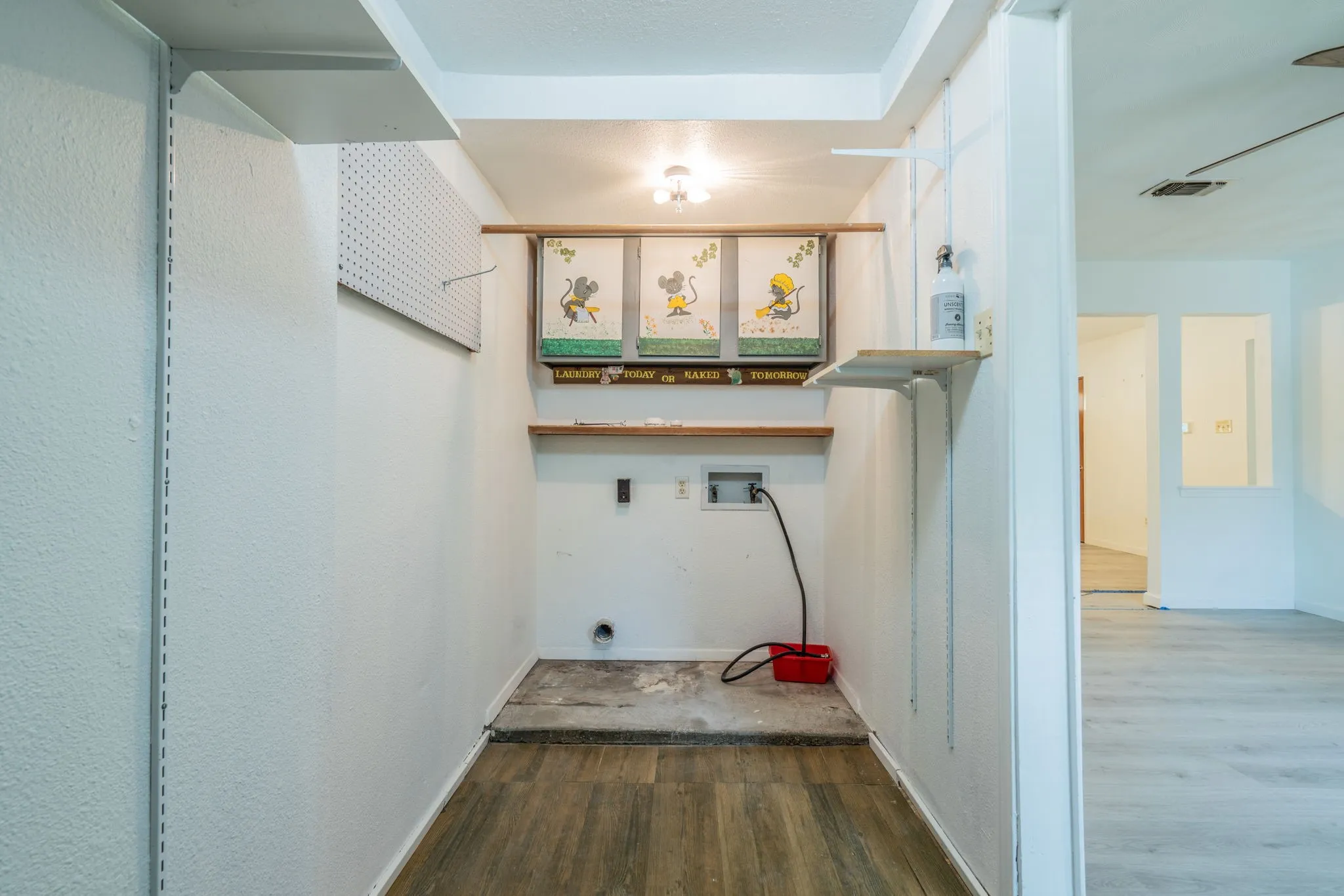Dedicated laundry alcove with wood-finish flooring and wall-mounted shelving