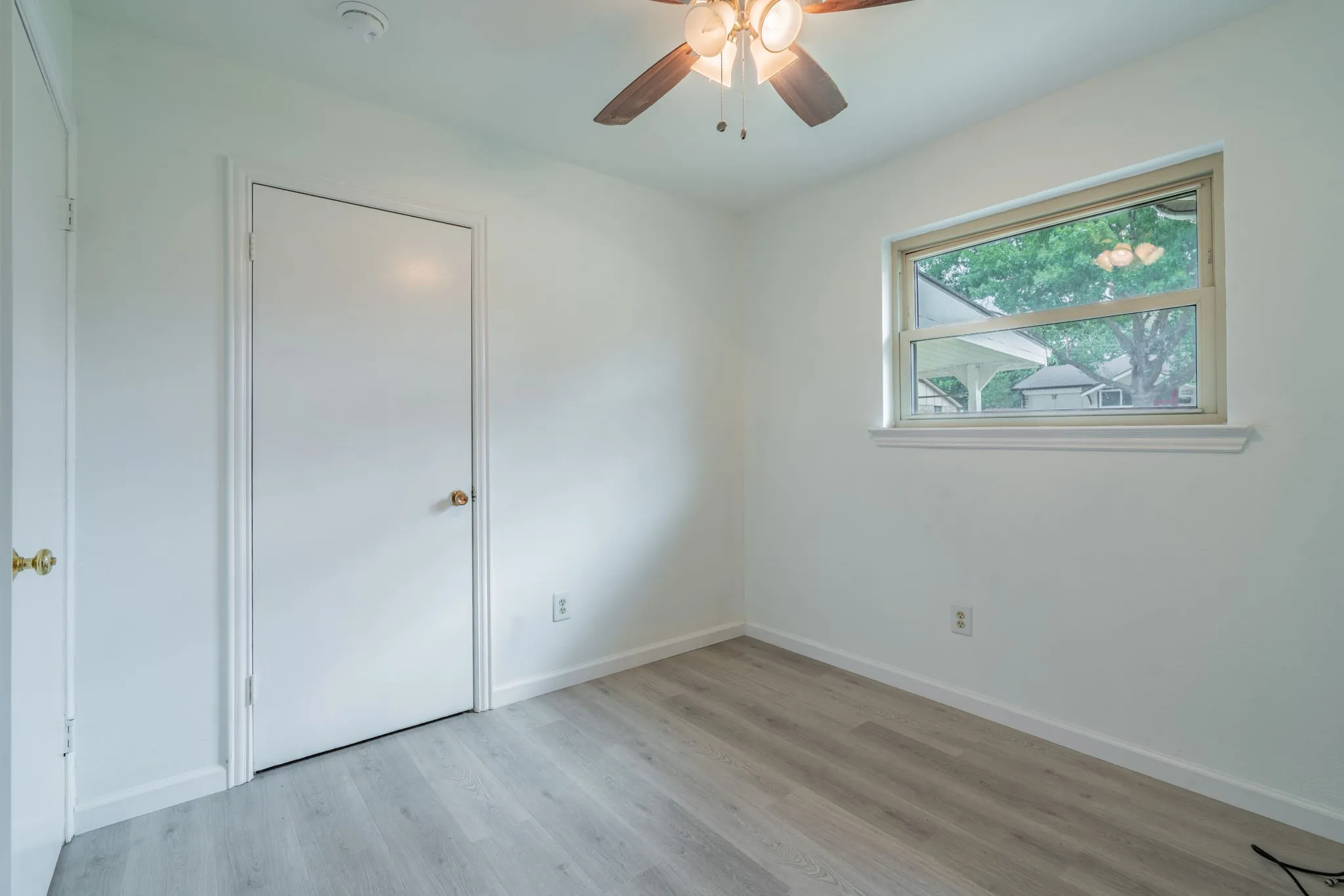 Wood-finish flooring, white walls, and a ceiling fan with integrated lighting