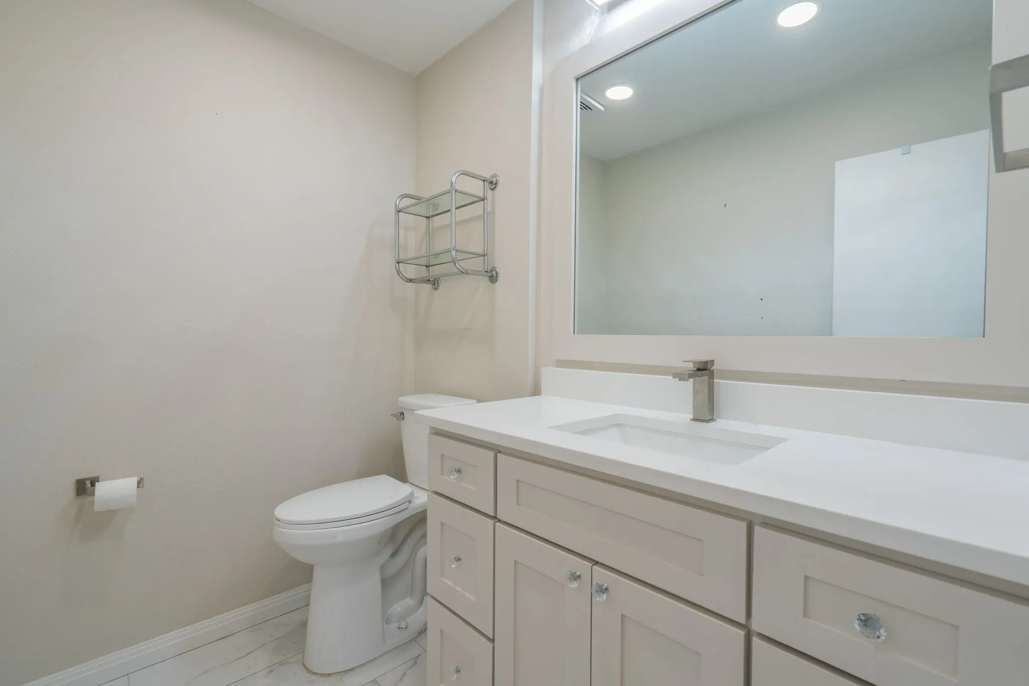 Vanity with an integrated rectangular sink, brushed nickel faucet, and a large mirror