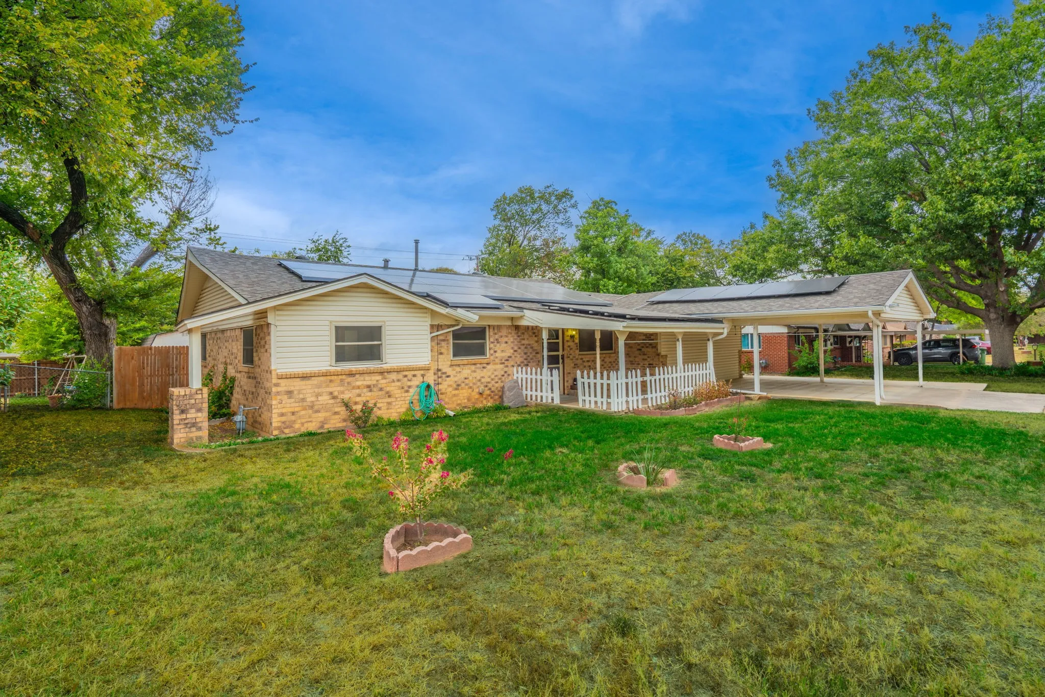 Brick and siding exterior with a covered front porch, white picket railing, and solar panels