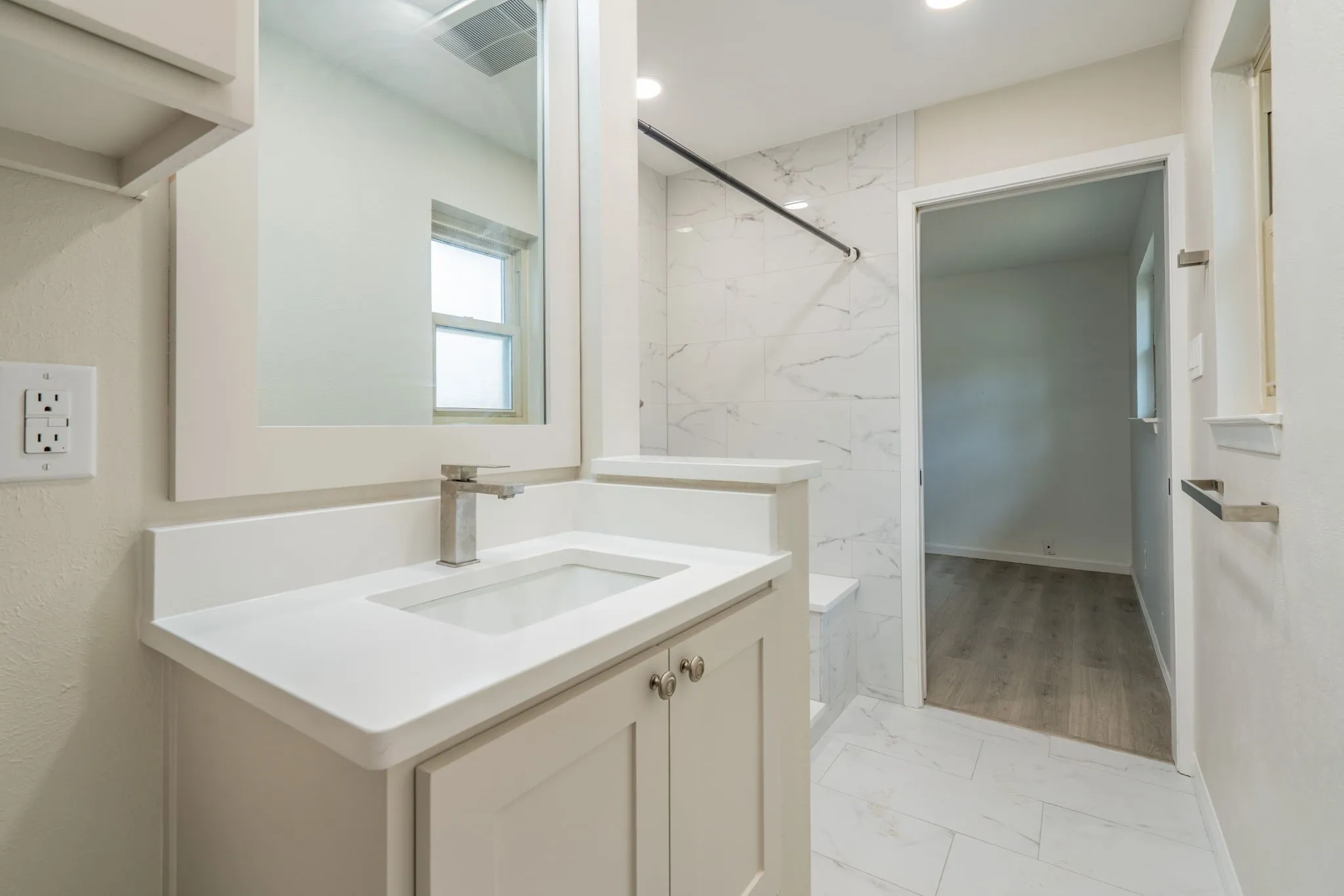 Bathroom featuring a vanity with an integrated sink, polished chrome faucet, under-cabinet storage, and white tile flooring
