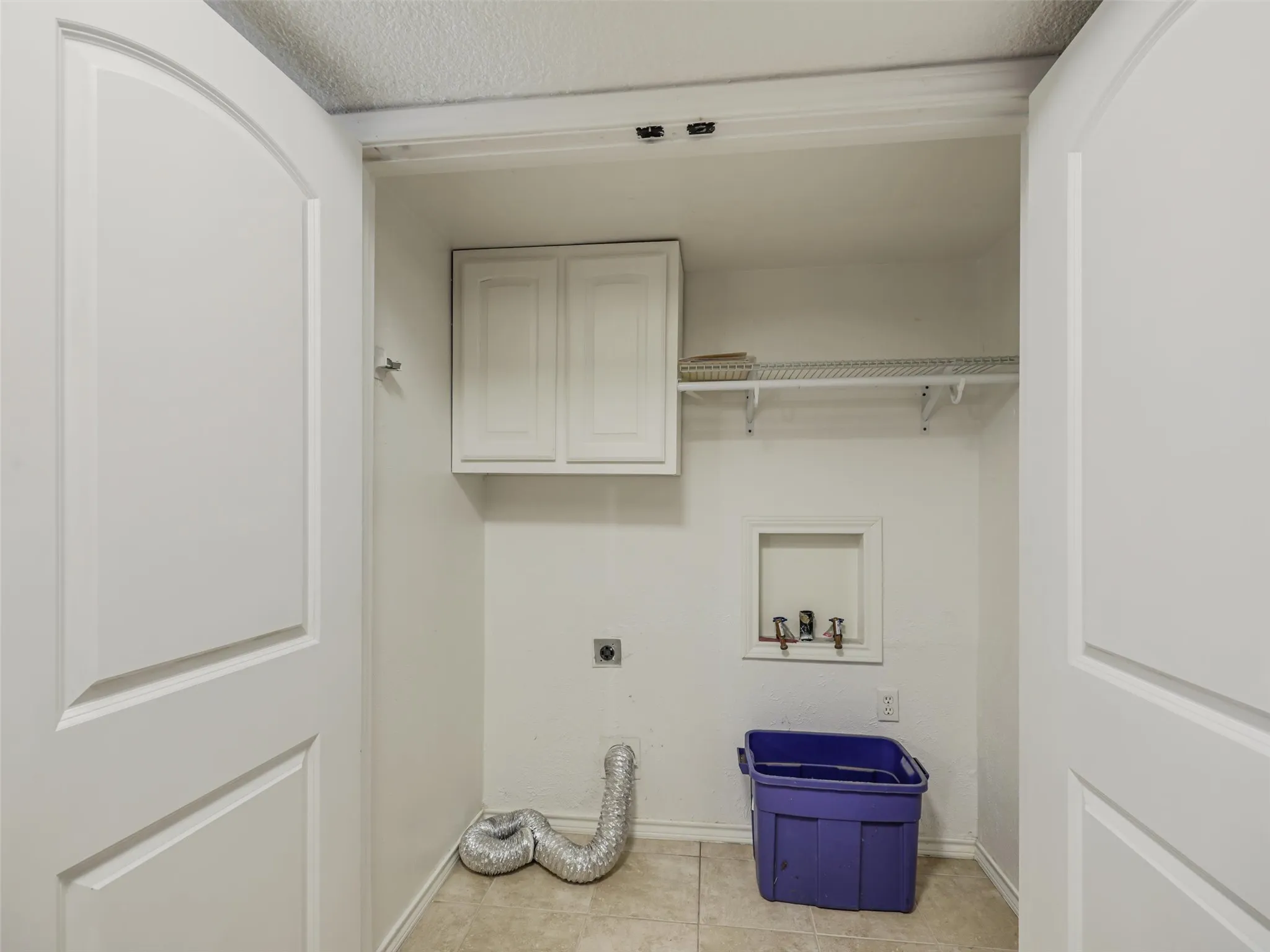 Laundry area with white cabinetry, tile flooring, and integrated shelving