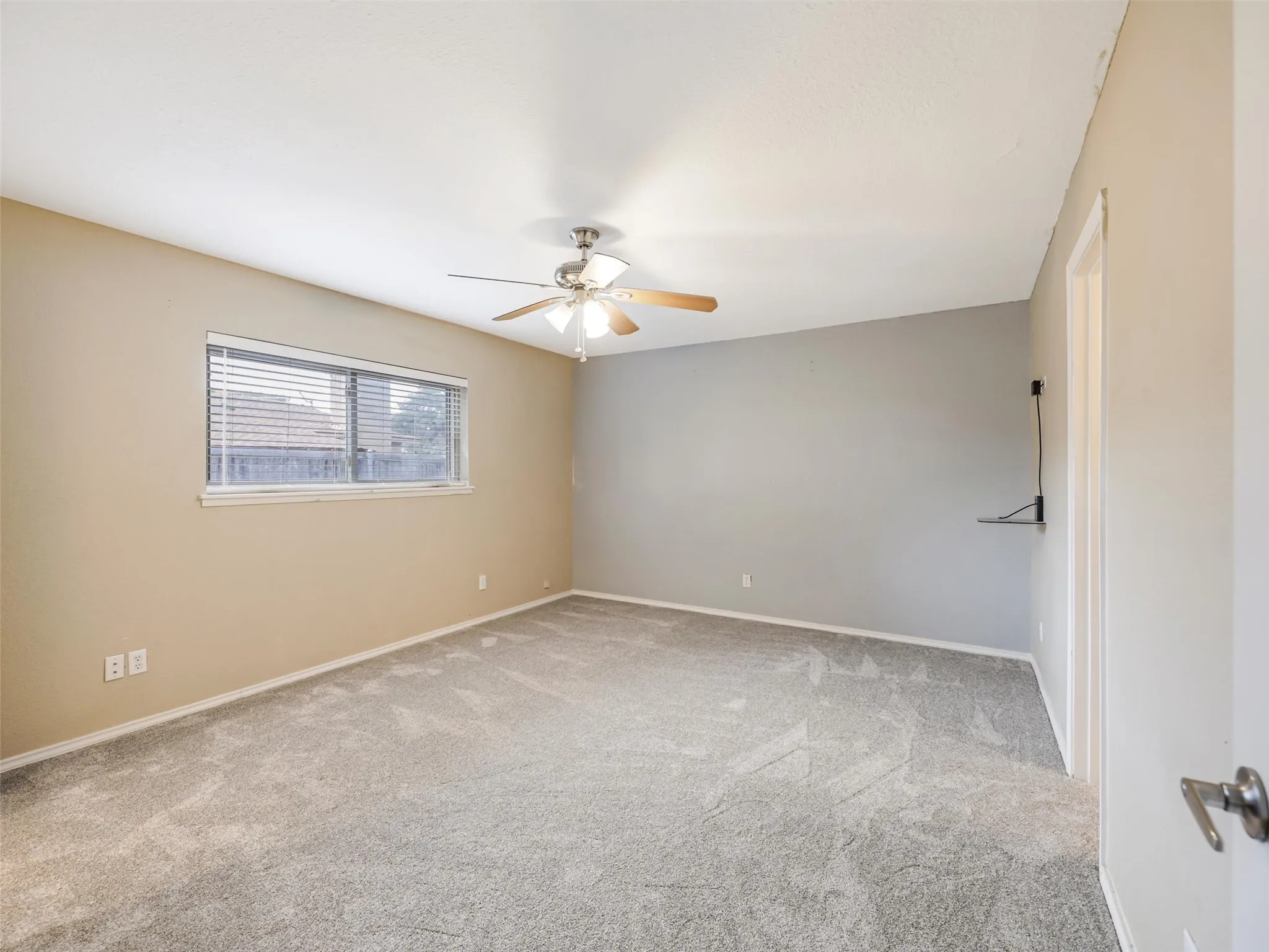 Wall-to-wall carpeting, window with blinds, ceiling fan with light fixture, and neutral wall tones
