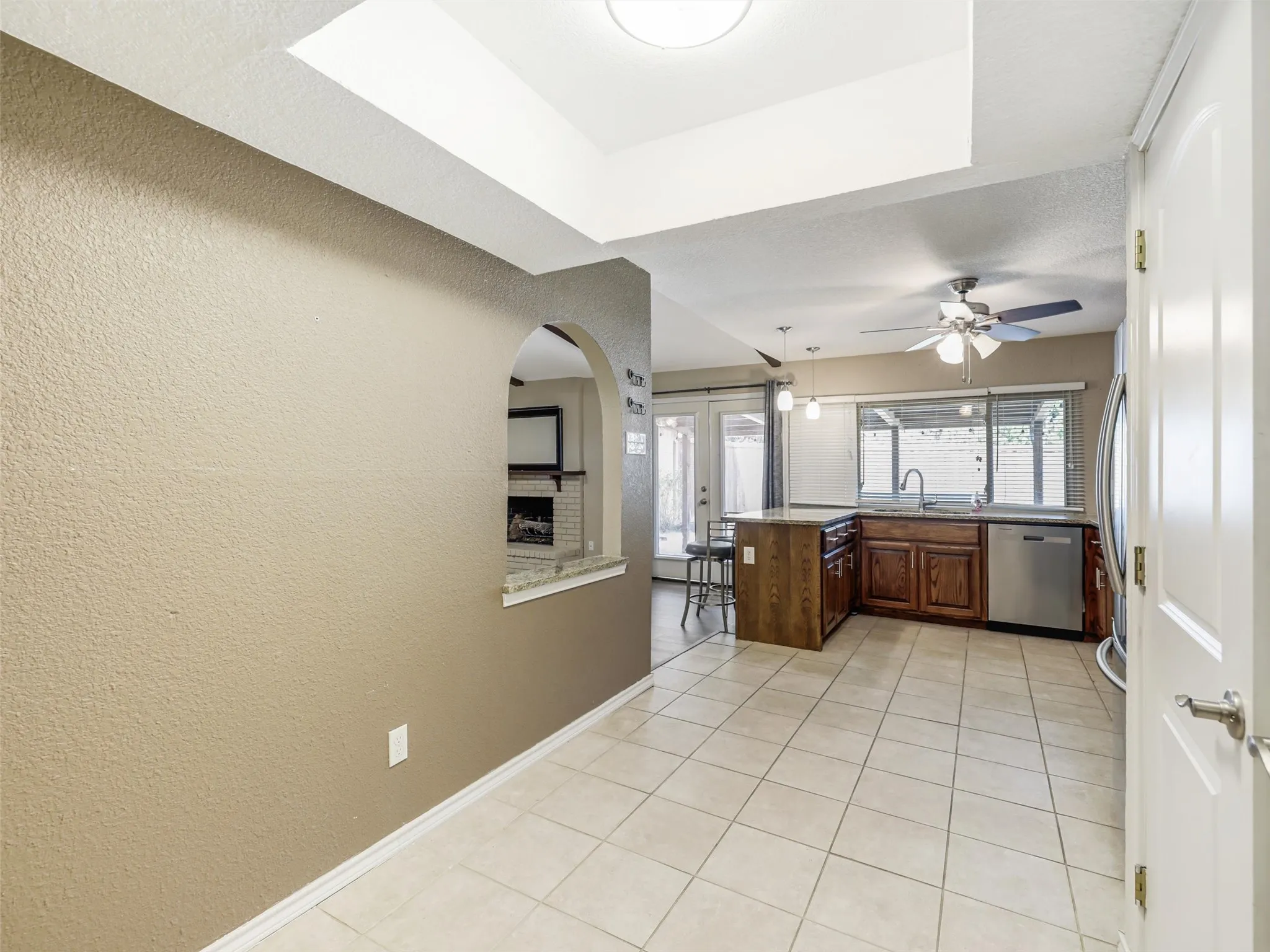 Kitchen featuring wood cabinetry, stainless steel dishwasher, and a center island with bar seating