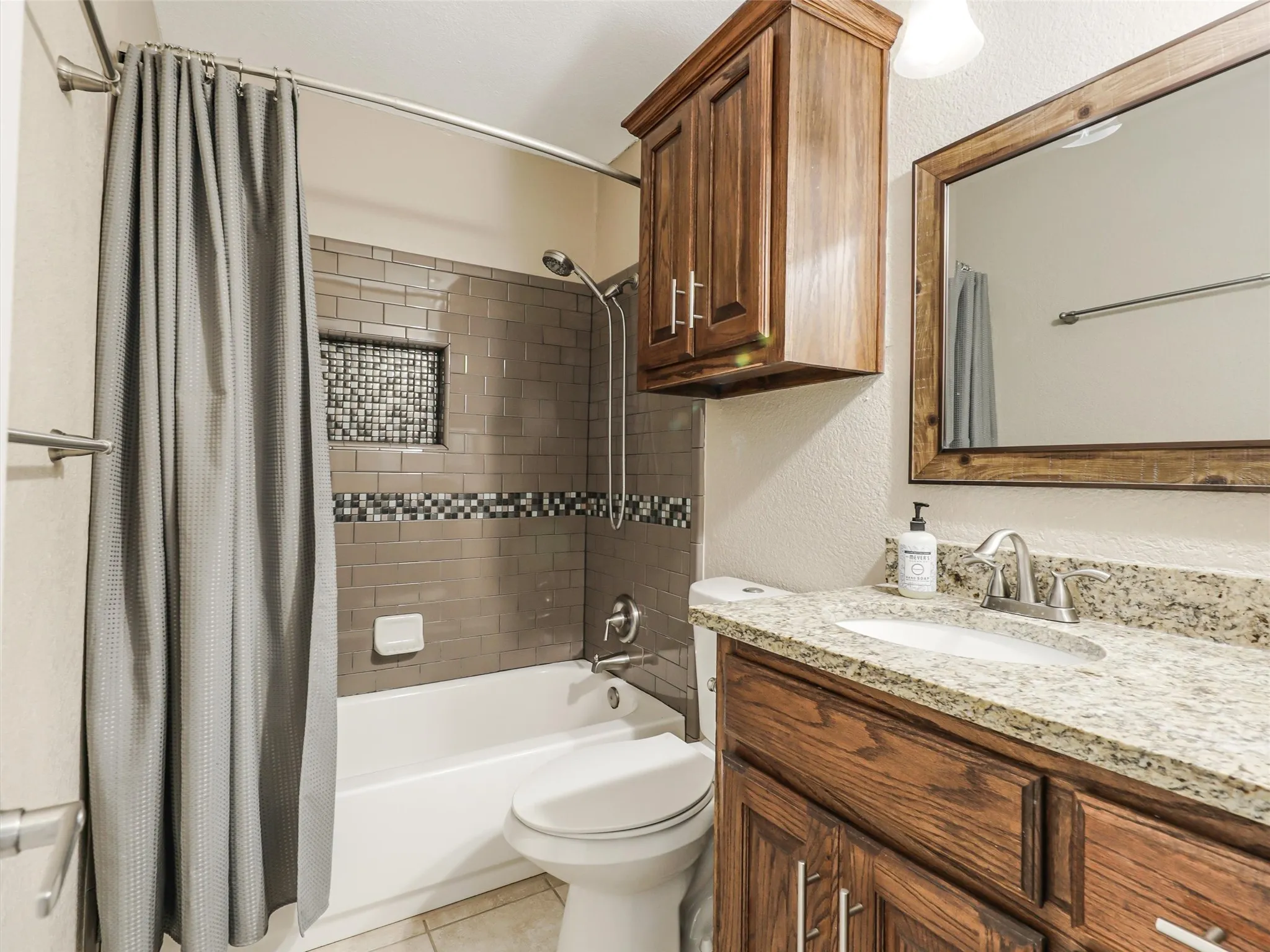 Built-in wood-finish vanity with a granite-style countertop and an undermount sink