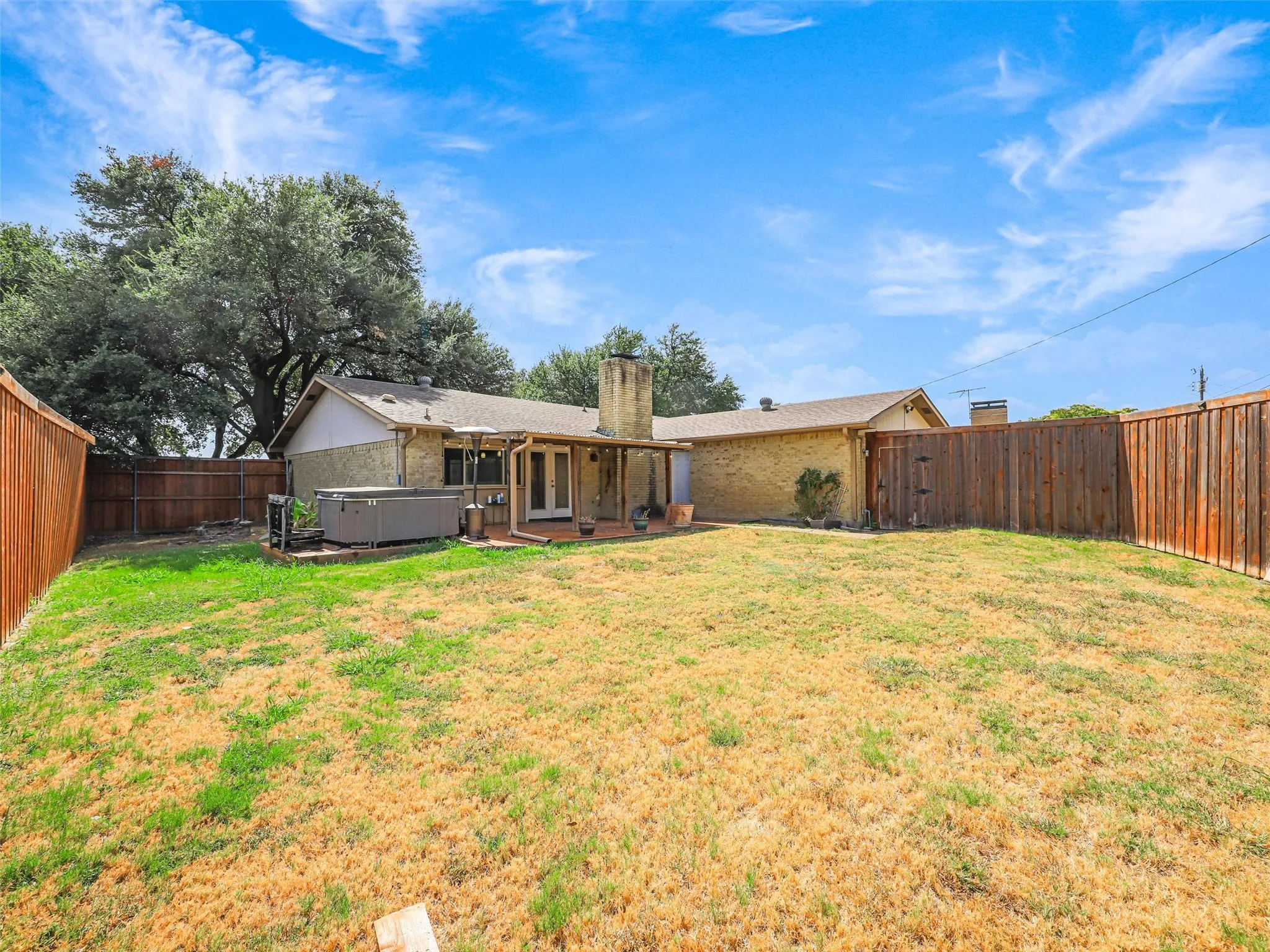 Expansive backyard with a covered patio, wood deck, and wood privacy fencing