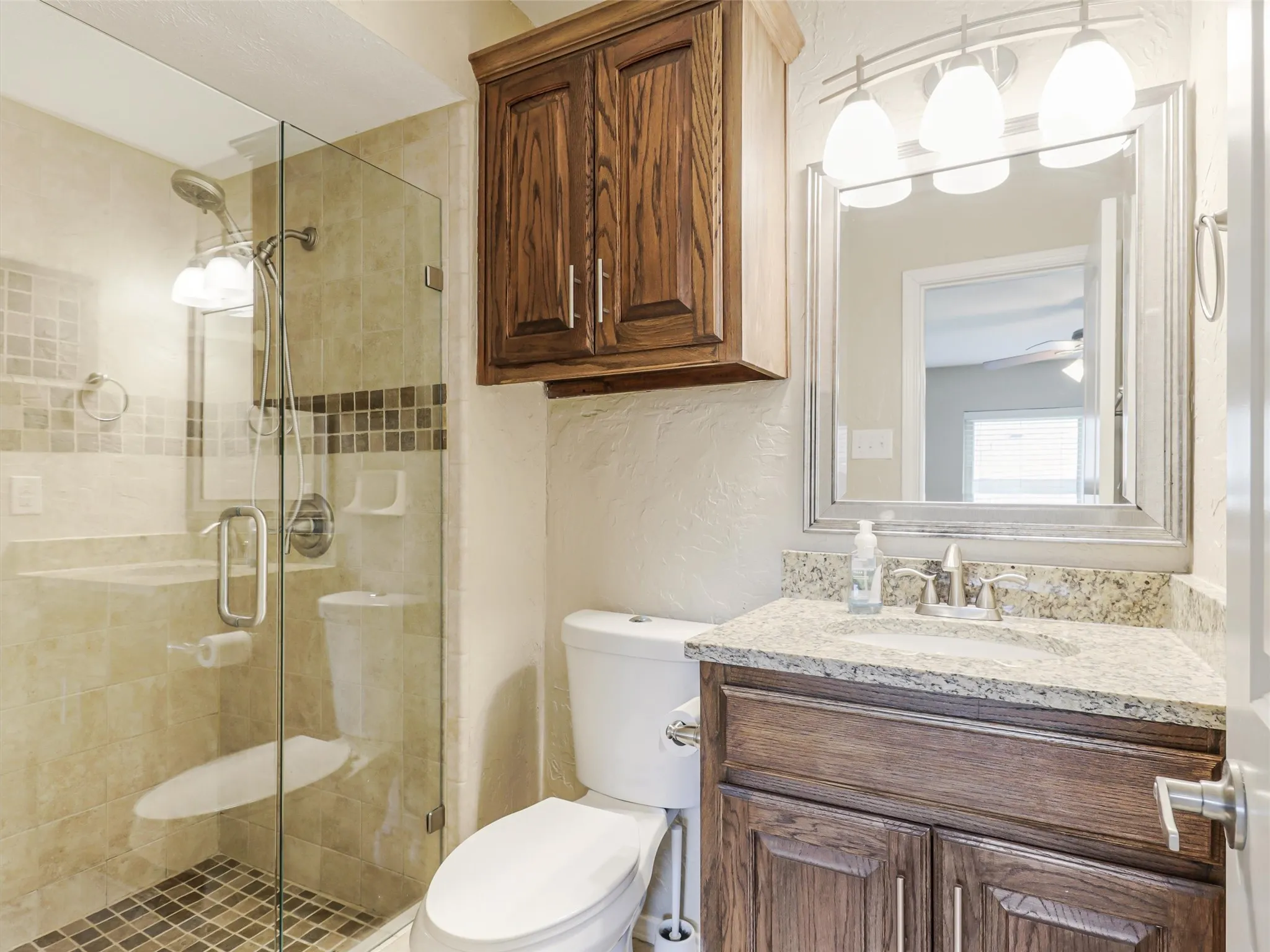 Walk-in shower with clear glass enclosure and mosaic tile accent