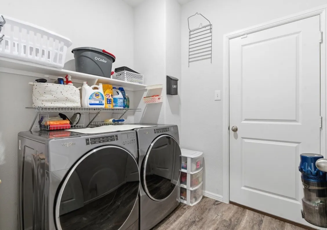 White walls, white paneled door, wood-finish flooring, and built-in shelving