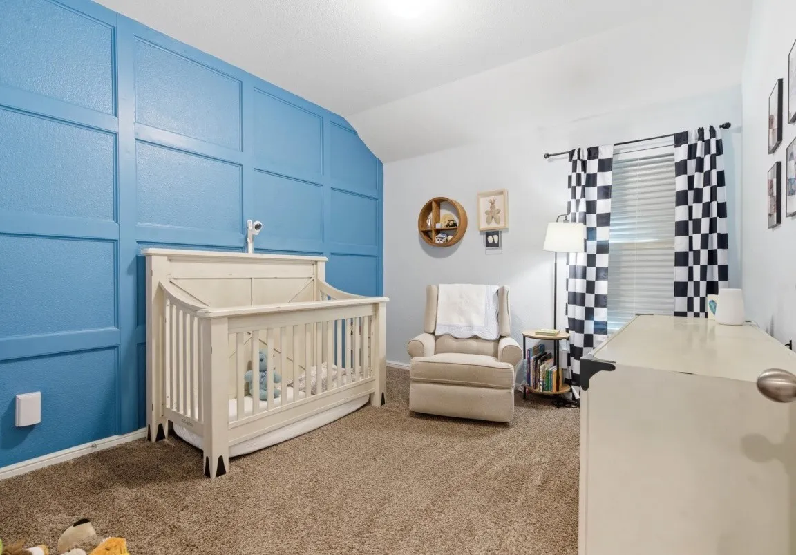 Accent wall with decorative paneling, light-colored carpeting, white baseboards, and window with blinds