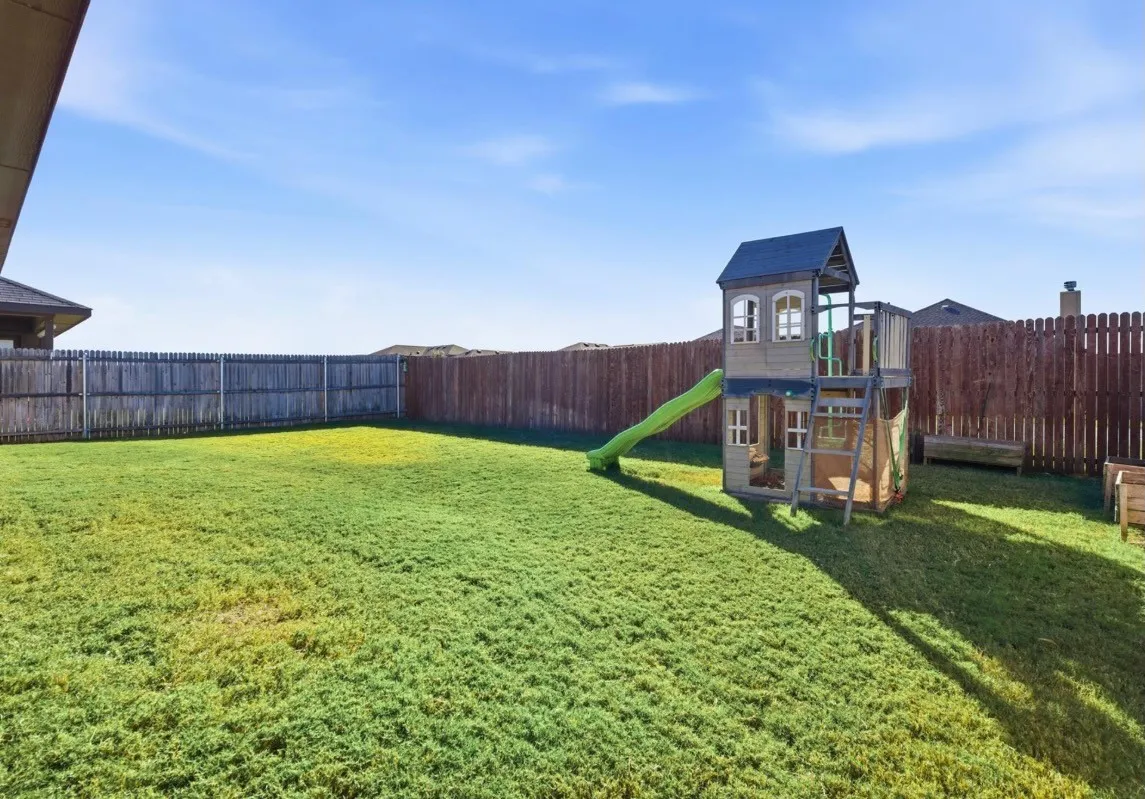 Expansive backyard featuring a manicured lawn and wood privacy fencing