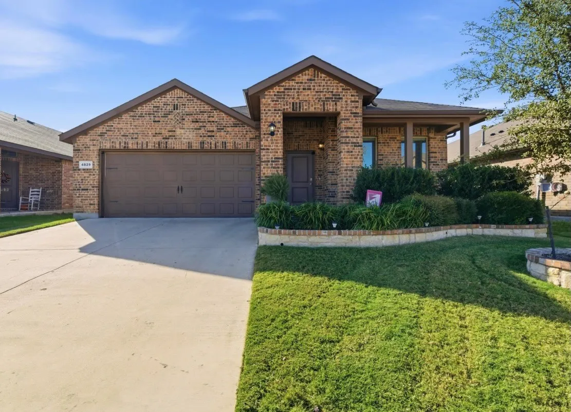 Brick facade with covered entry, attached two-car garage, and concrete driveway