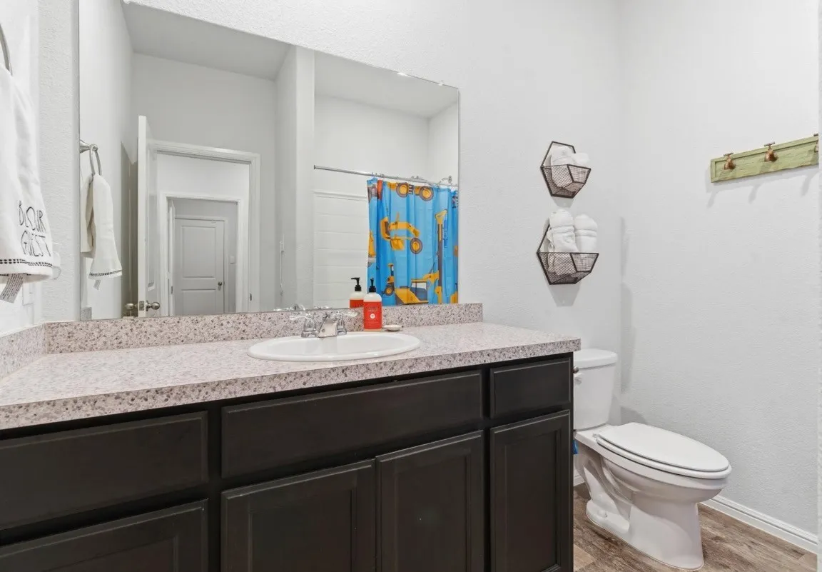 Vanity with an integrated sink, dark wood-finish cabinetry, and a speckled countertop