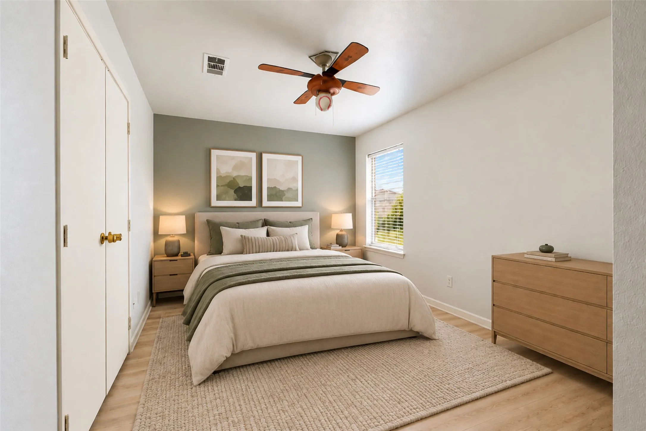 Wood-finish flooring, built-in closet with bifold doors, window with horizontal blinds, ceiling fan, and accent wall
