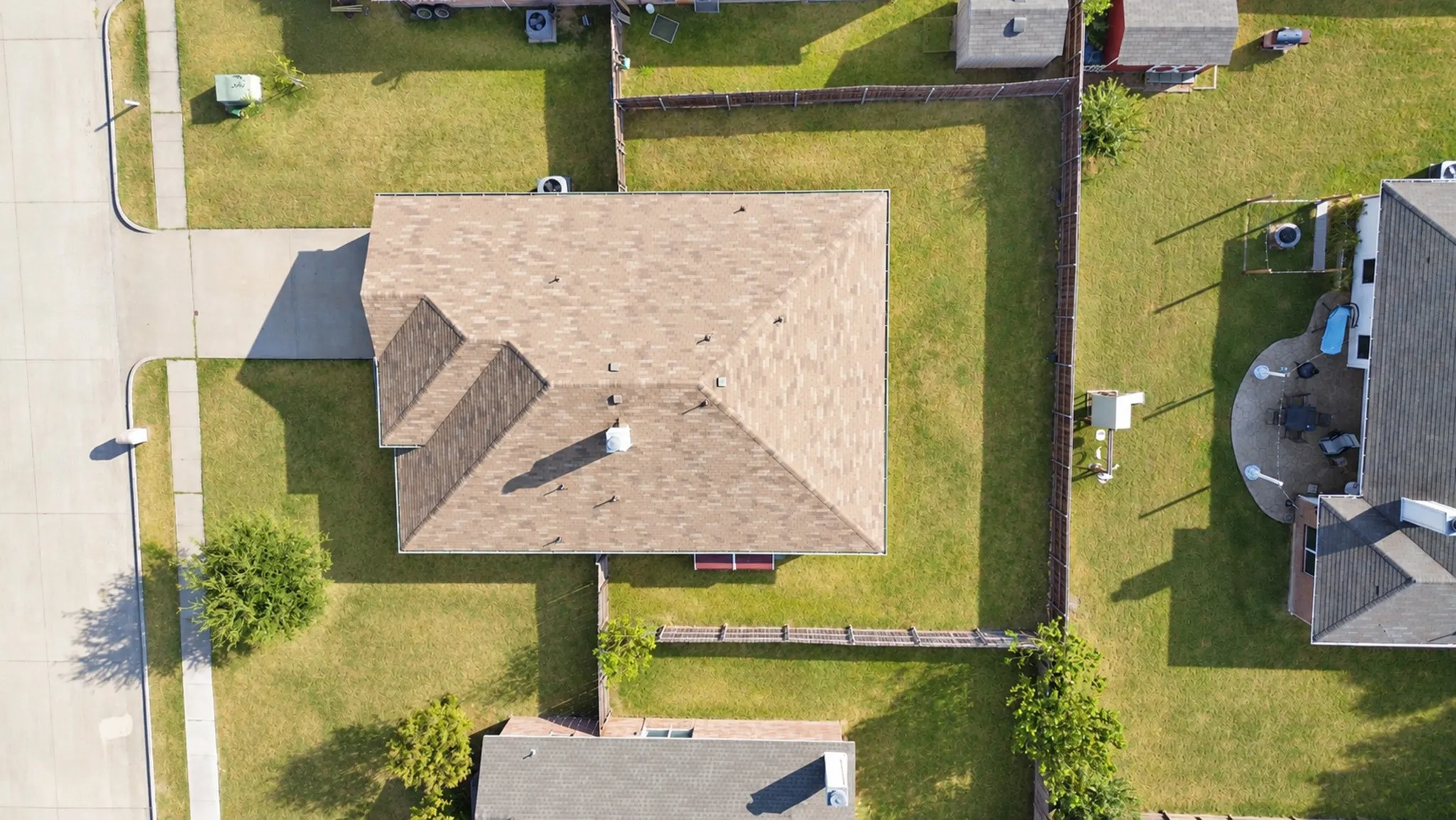 Asphalt shingle roof, well-maintained lawn, privacy fencing, concrete driveway, and concrete walkways