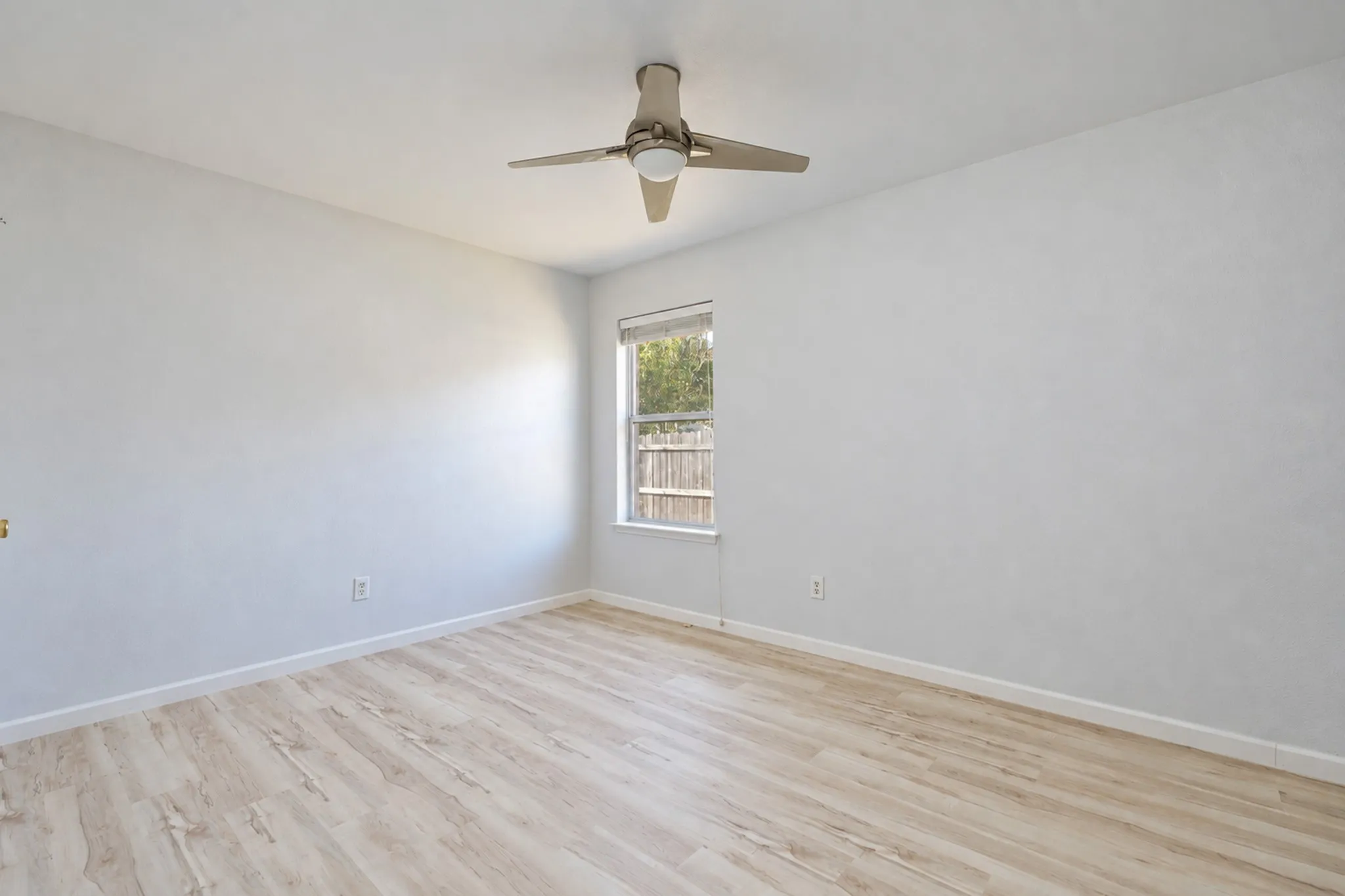 Wood-finish flooring, neutral wall tones, and a ceiling fan with integrated lighting