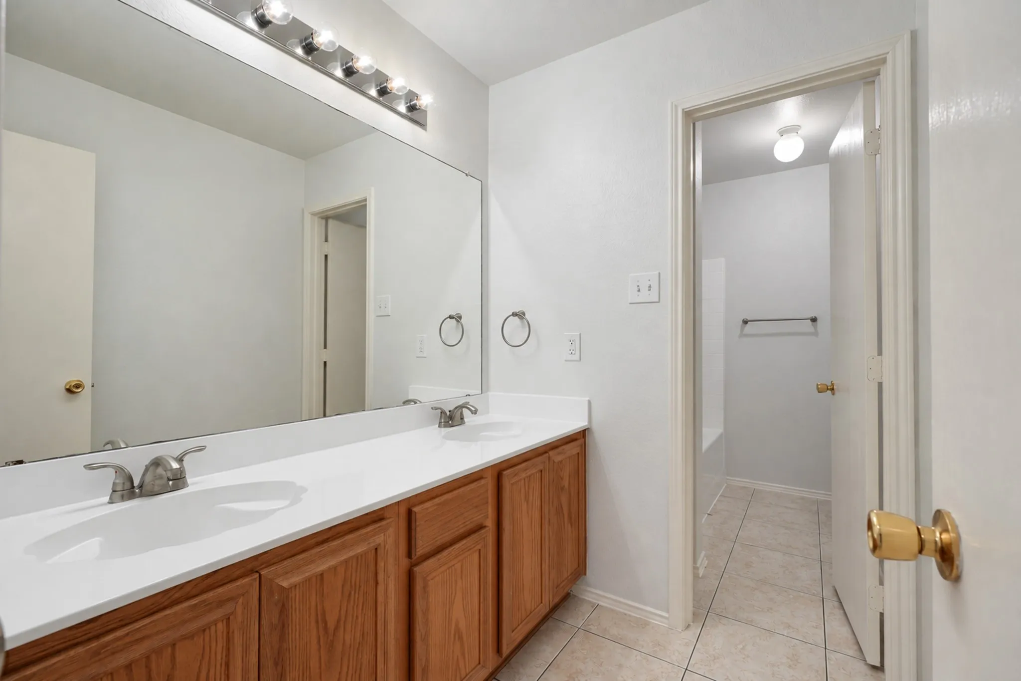 Double vanity with wood-finish cabinetry, dual undermount sinks, and brushed nickel faucets