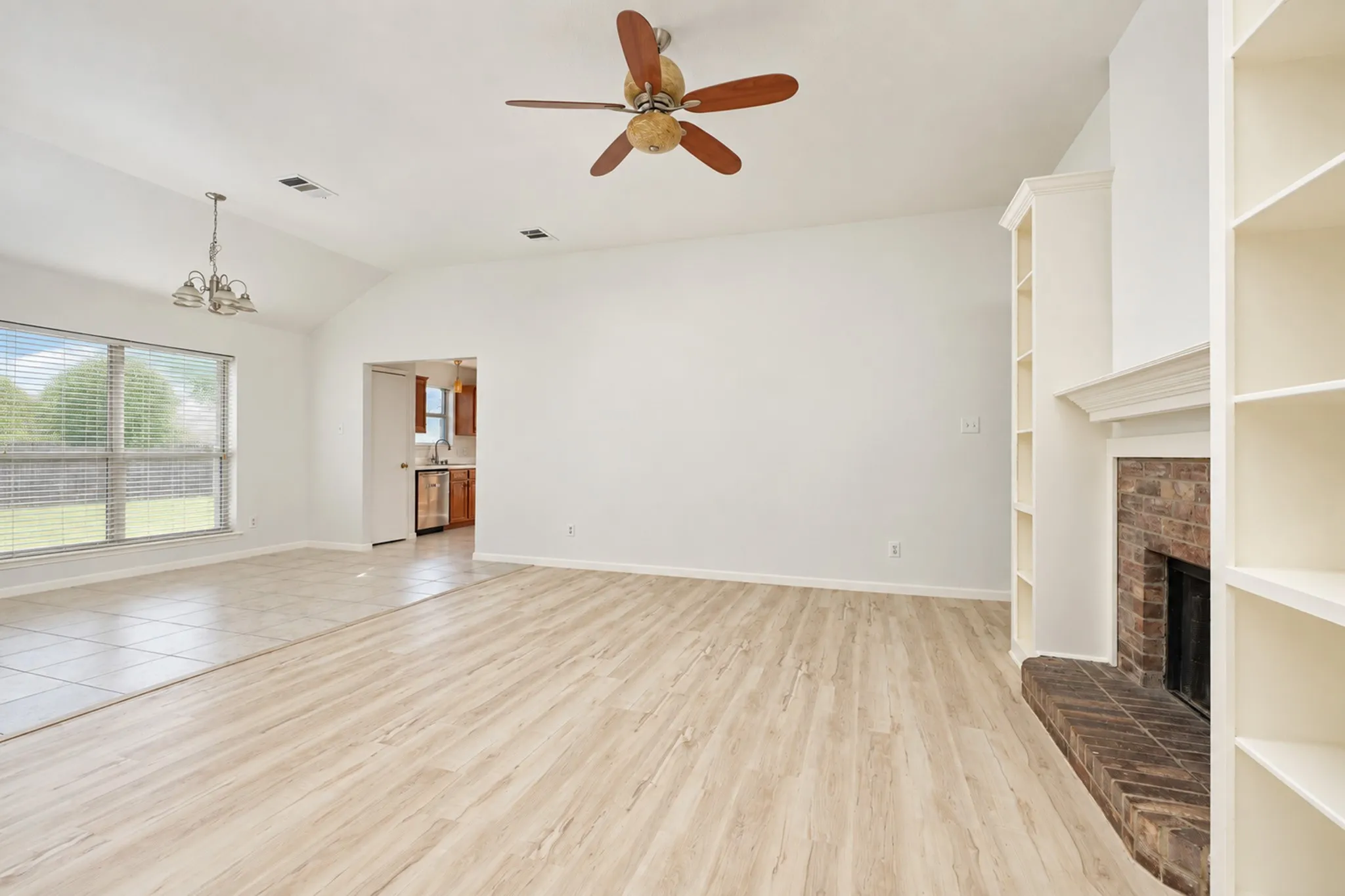 Vaulted ceiling, wood-finish flooring, ceiling fan, brick fireplace, built-in shelving