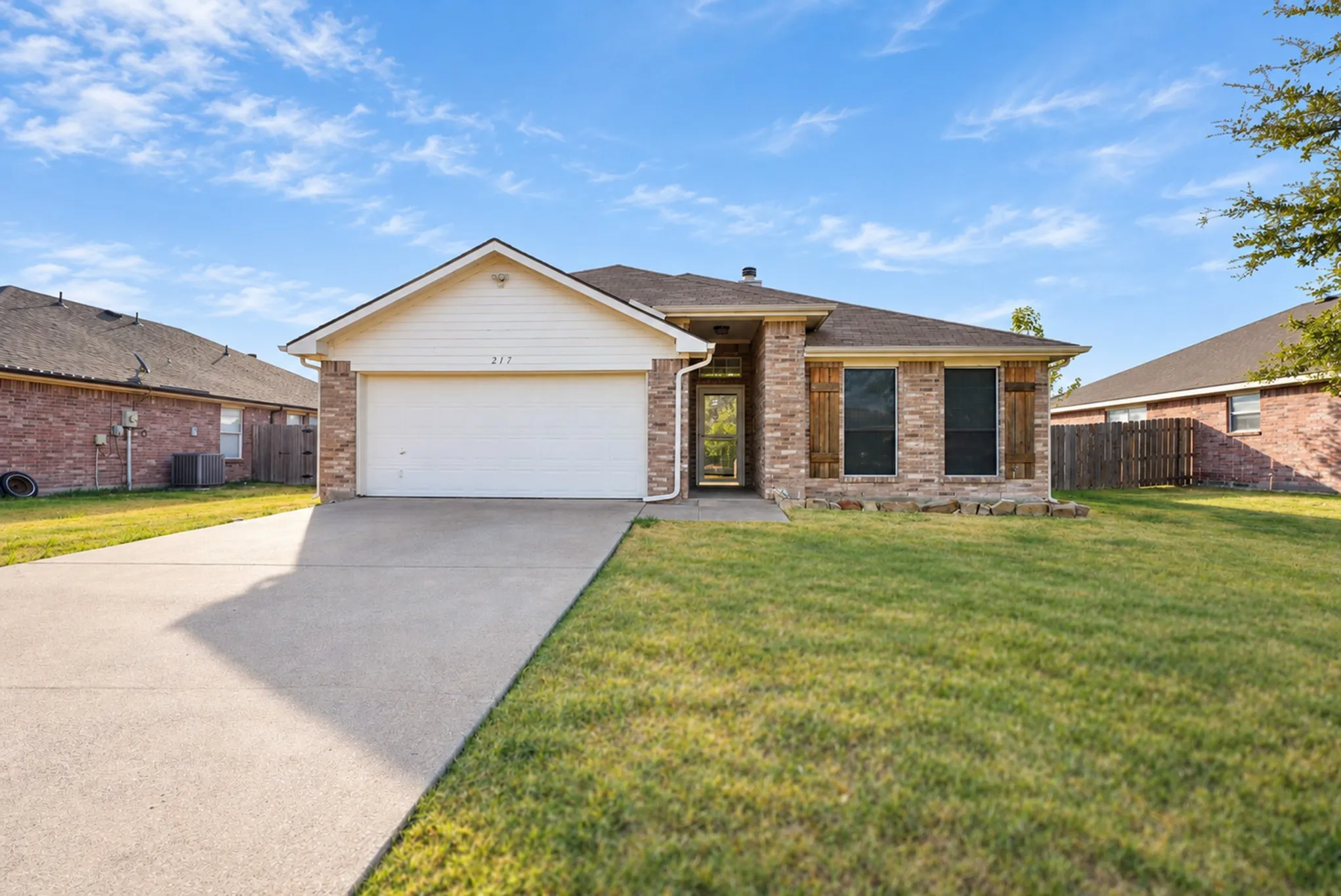 Brick and siding exterior with stone accents, attached garage, and concrete driveway