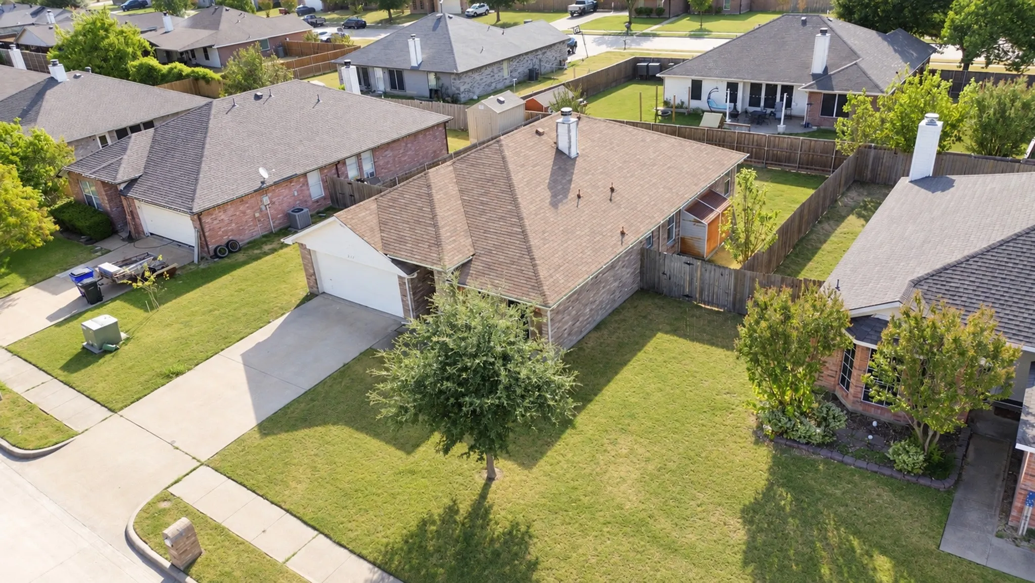 Brick exterior, attached garage, gabled roof, fenced backyard, and mature landscaping
