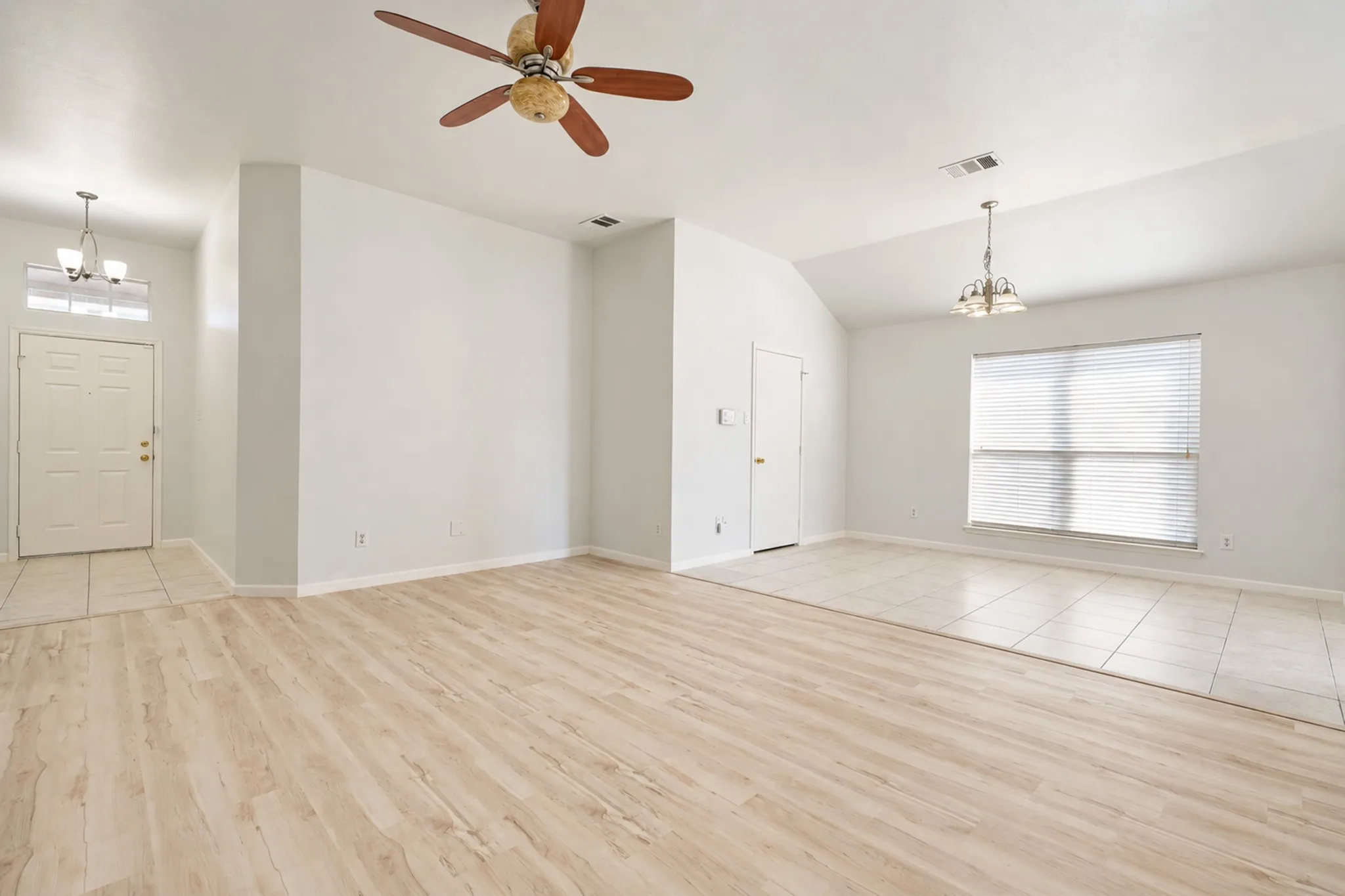 Vaulted ceiling with a ceiling fan, wood-finish flooring, tiled flooring, and a large window