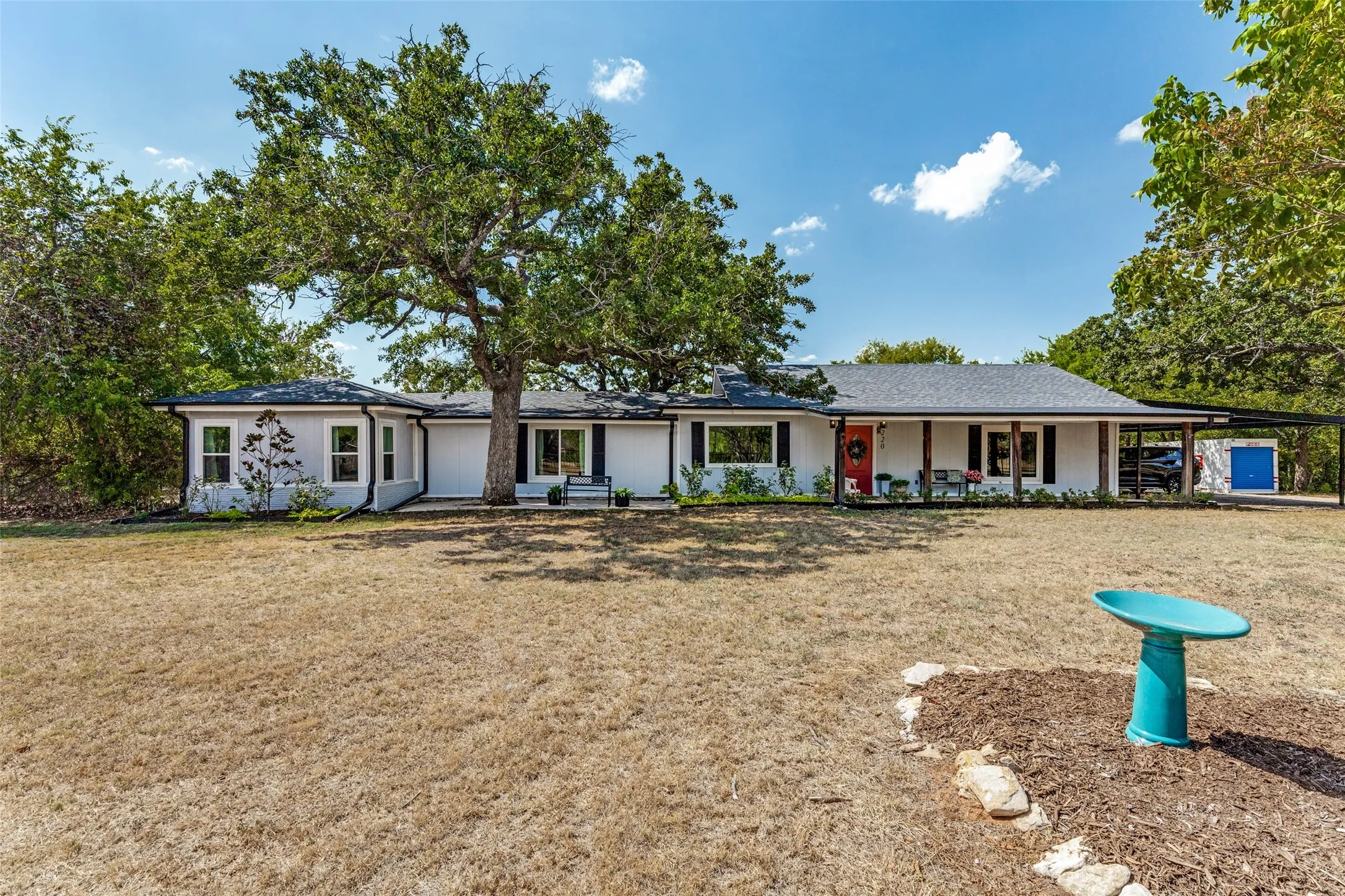 Ranch-style residence featuring white siding, a covered front porch with dark support columns, and a dark asphalt shingle roof