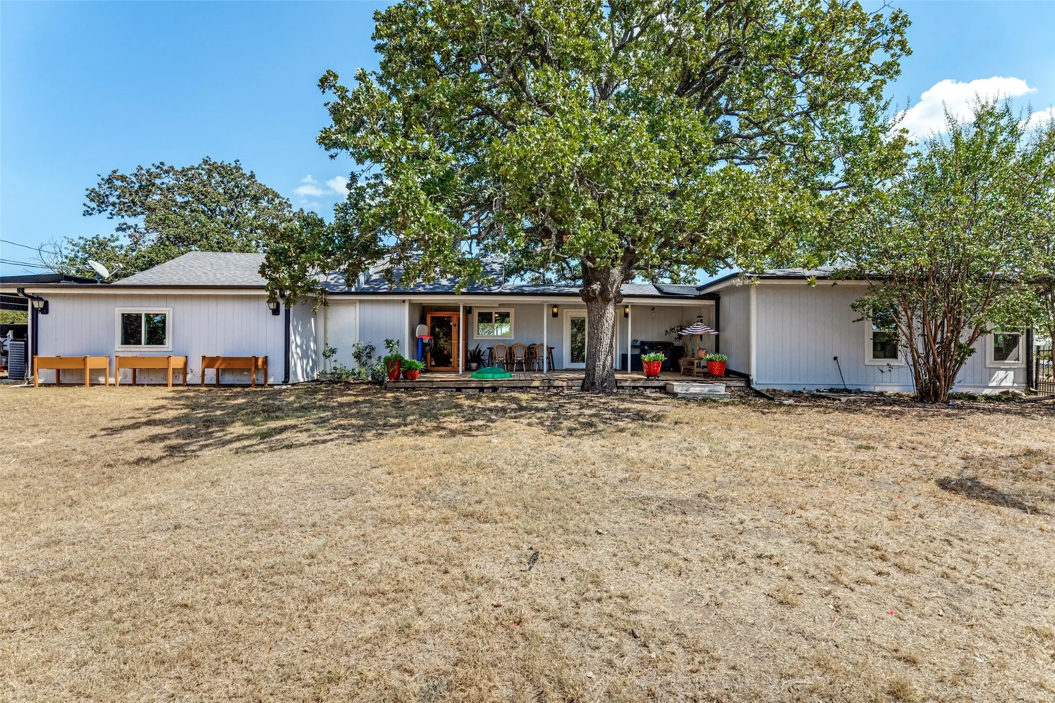 Expansive backyard featuring mature trees, a covered patio, and a shingle roof