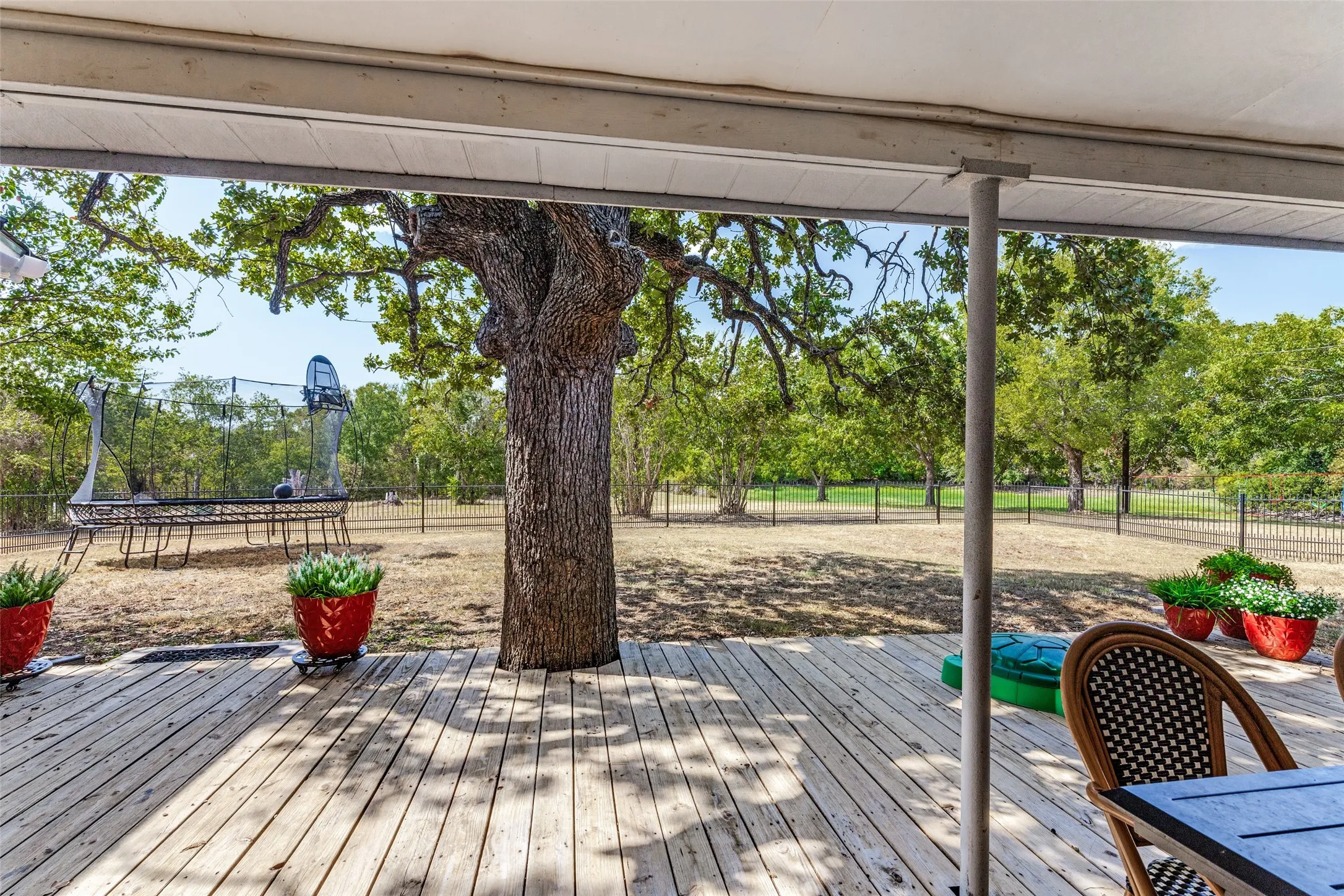 Covered wood deck with a large mature tree and a fenced perimeter