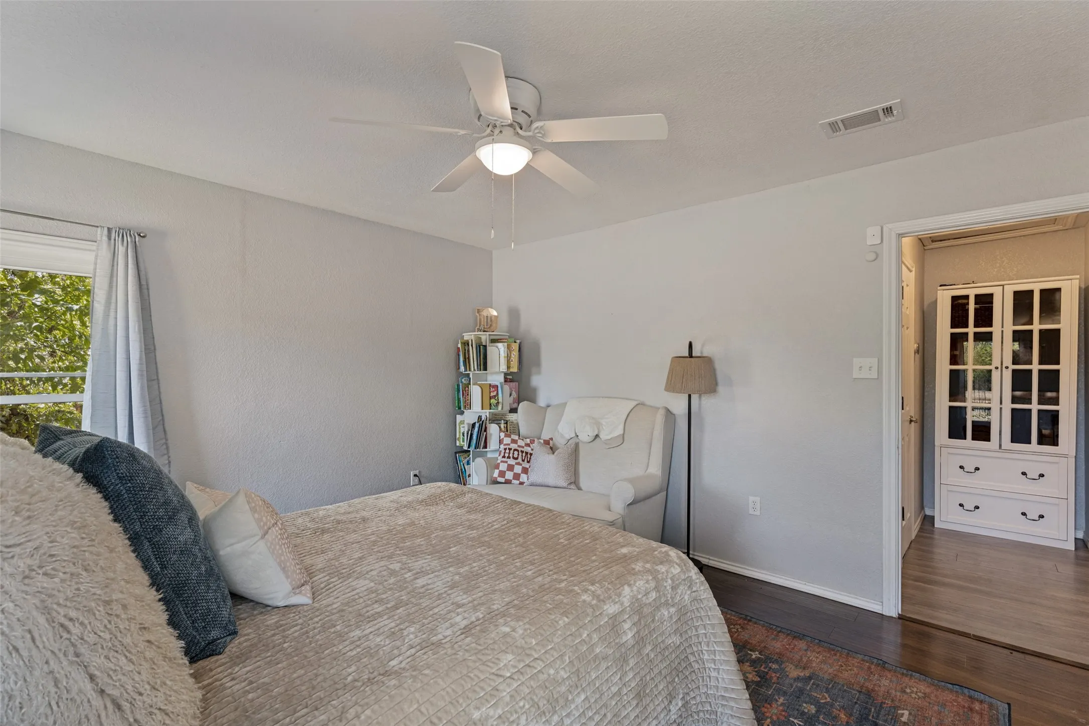Ceiling fan with integrated lighting, wood-finish flooring, white trim, and a built-in display cabinet
