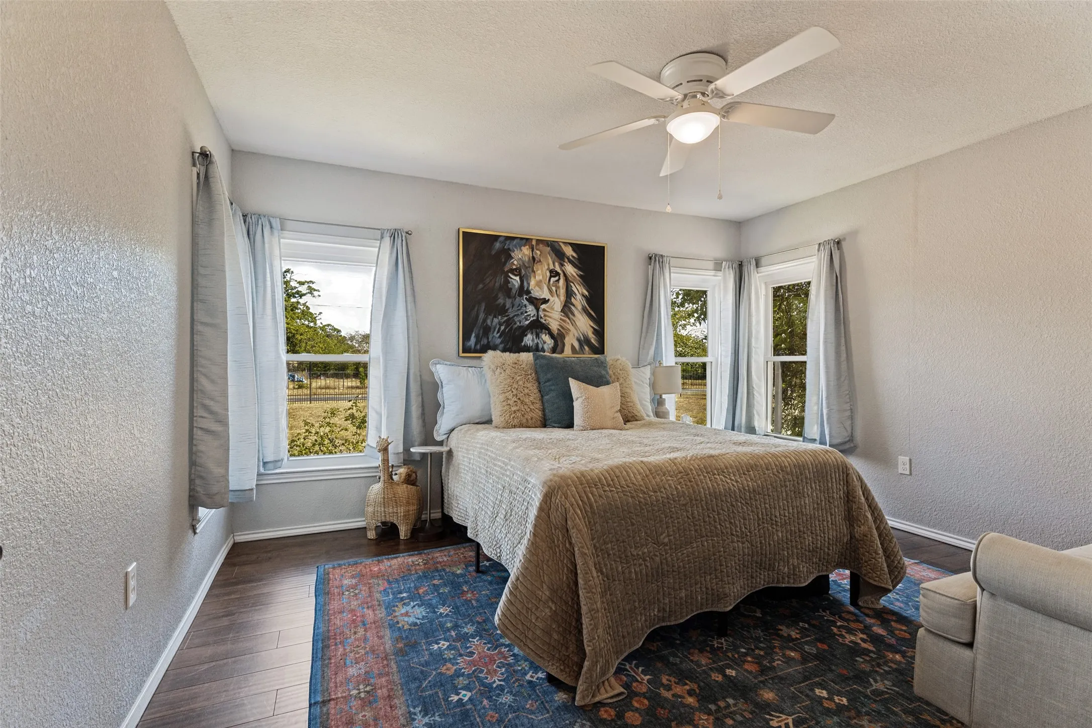 Wood-finish flooring with a ceiling fan light fixture and multiple windows